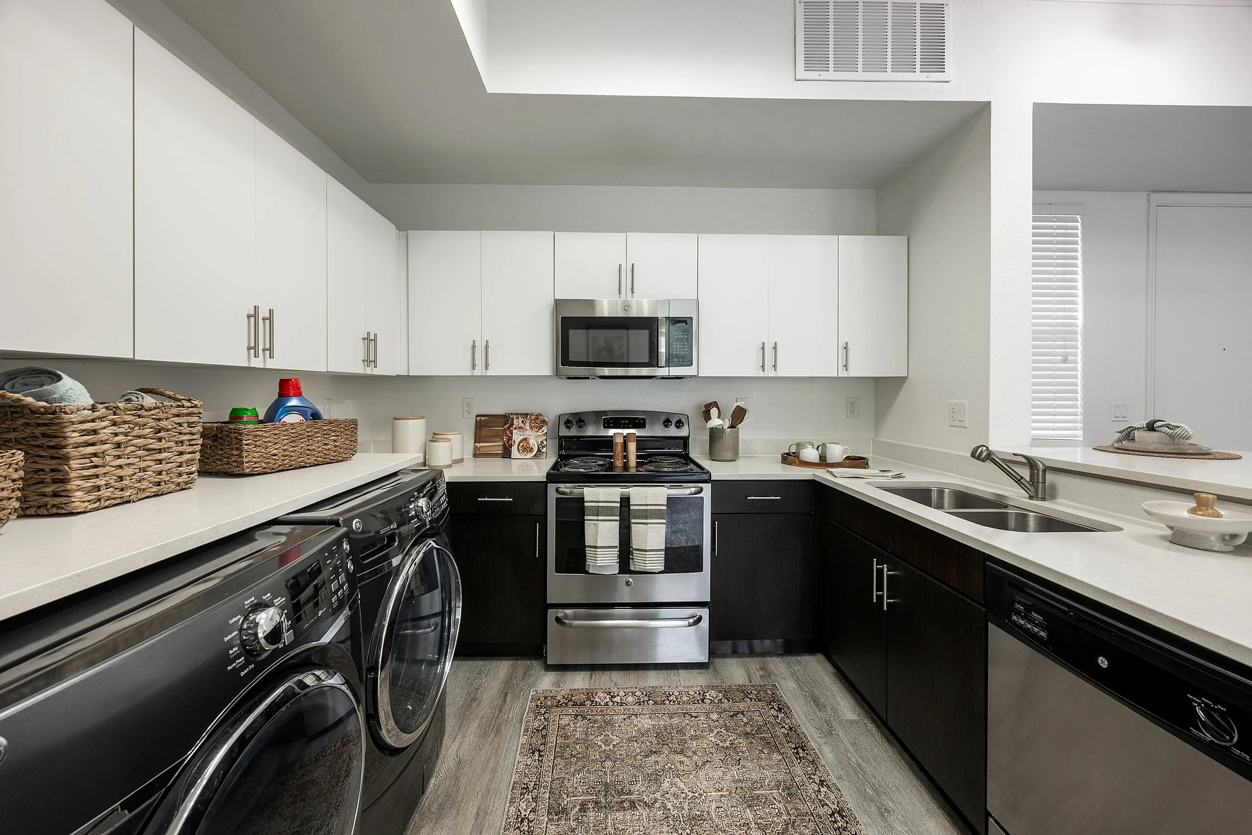 Modern kitchen with sleek black and white cabinetry, stainless steel appliances, and a convenient laundry area, creating a stylish and functional space.