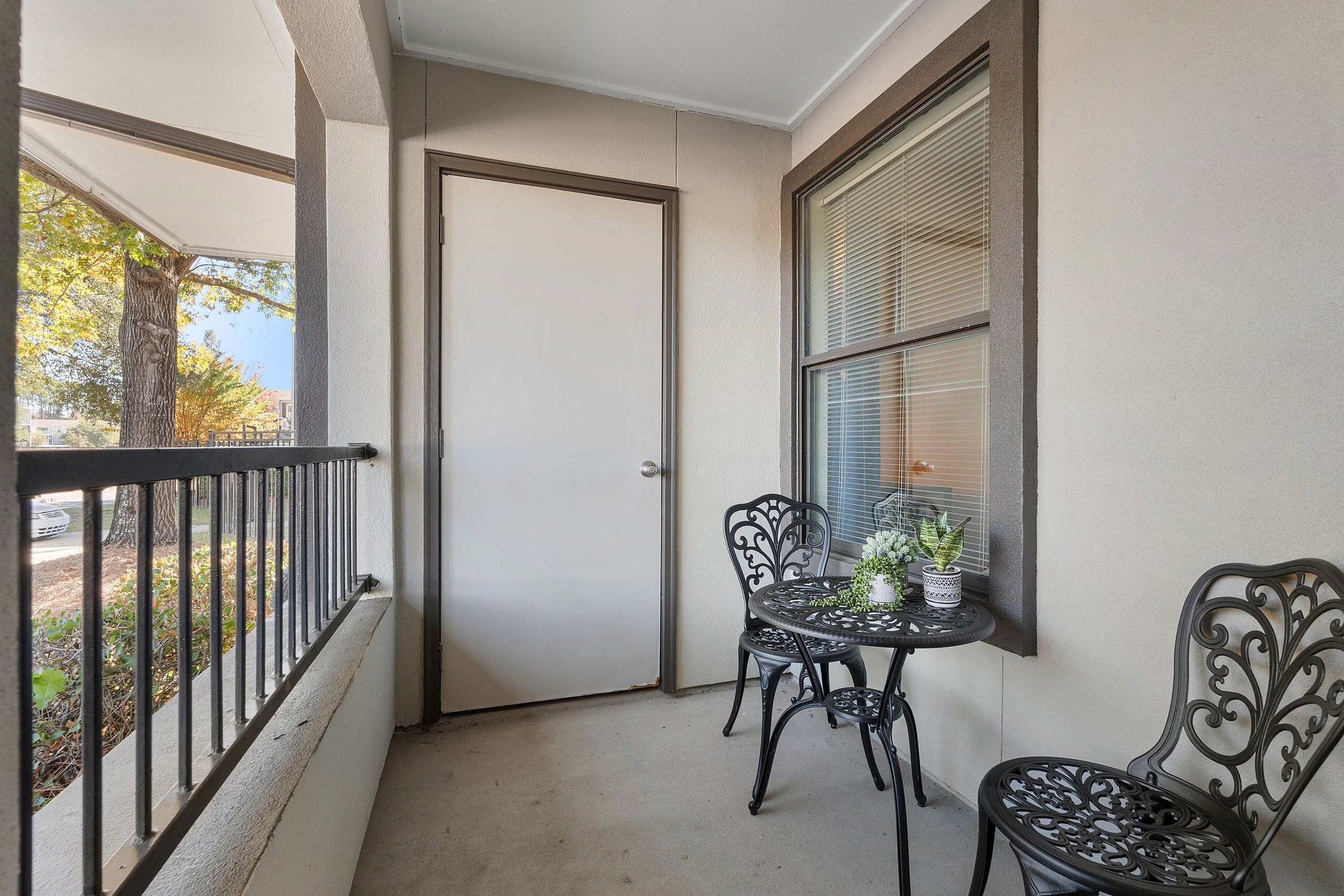 Charming balcony retreat with elegant wrought iron furniture and lush greenery, perfect for relaxing and enjoying the serene surroundings.
