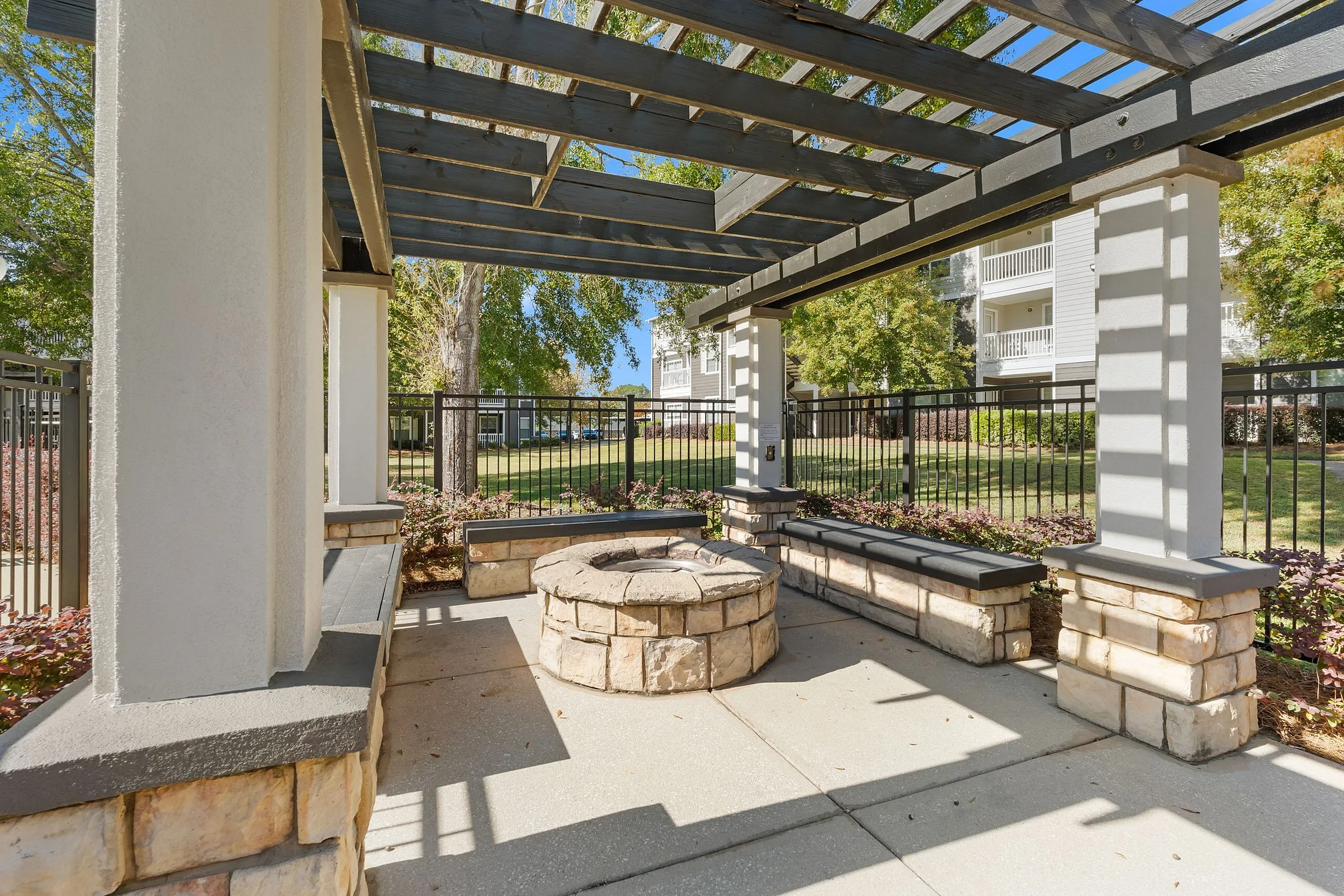 Inviting outdoor patio with pergola and cozy stone fire pit, ideal for relaxation and gatherings.