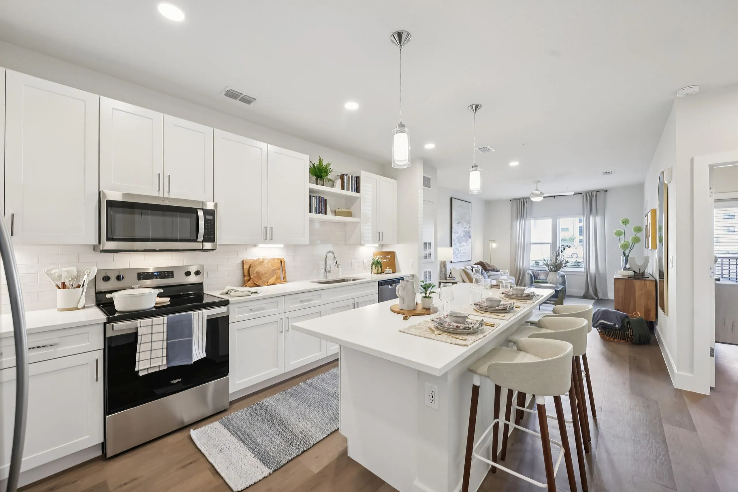 Inviting modern kitchen with sleek white cabinetry, a stylish breakfast bar, and open living area filled with natural light.