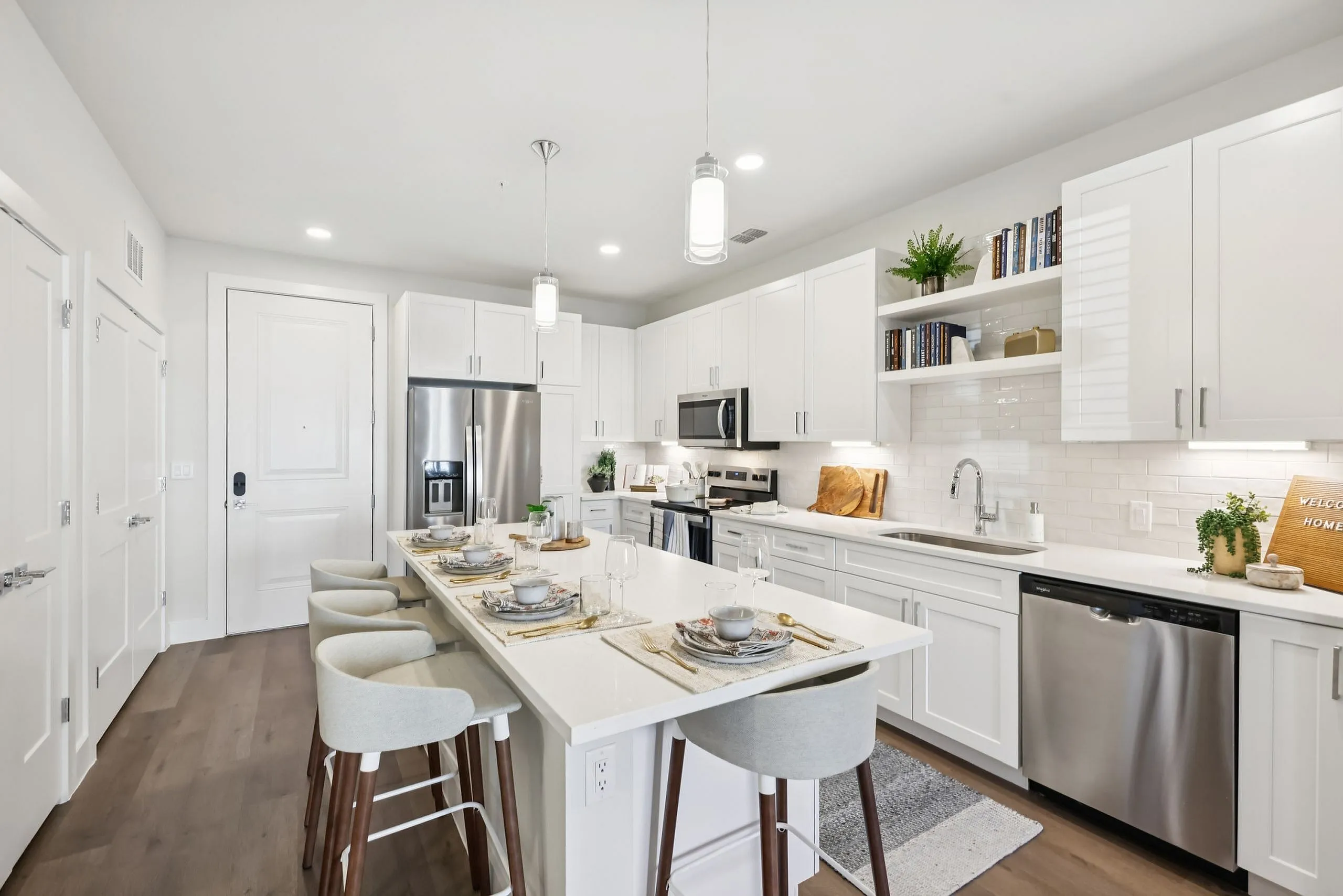 Modern and elegant kitchen with a spacious island, sleek white cabinetry, stainless steel appliances, and stylish bar seating.