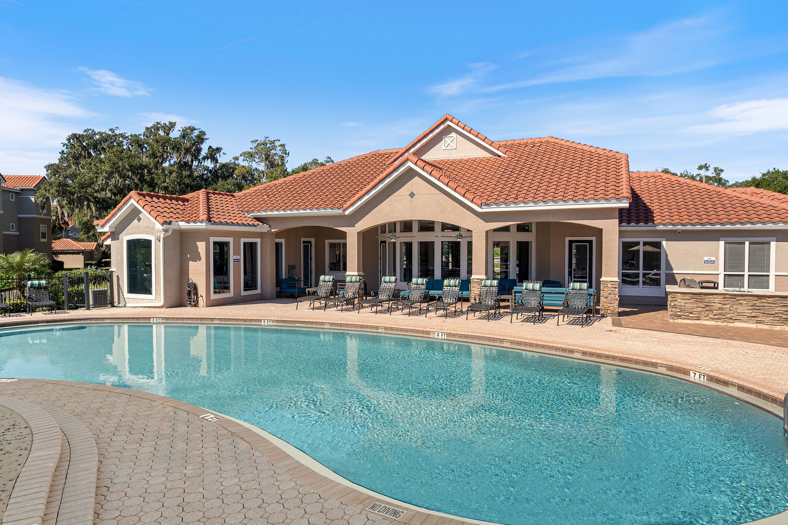Luxurious Mediterranean-style clubhouse with a pristine pool and sun loungers, perfect for relaxation.