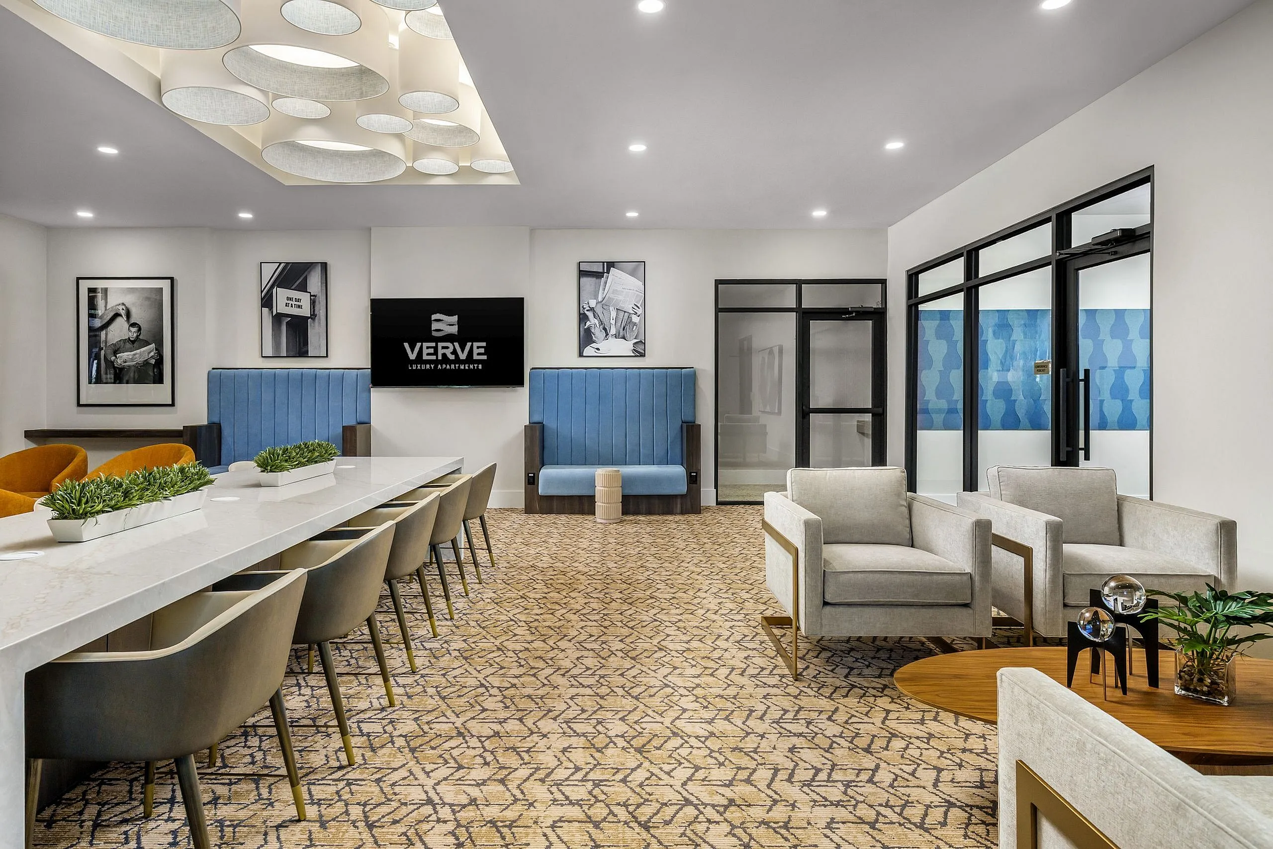 Elegant apartment lounge with modern decor, featuring comfortable seating, stylish lighting, and a sleek communal table, perfect for socializing.