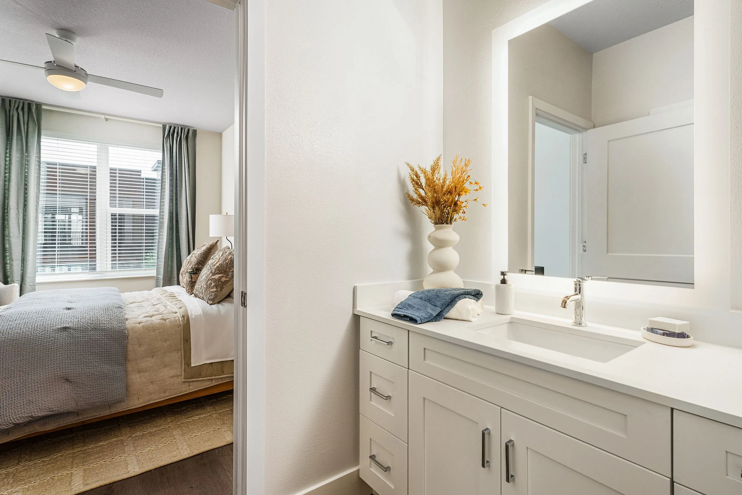 Bright and modern bedroom with elegant furnishings and a pristine bathroom vanity.