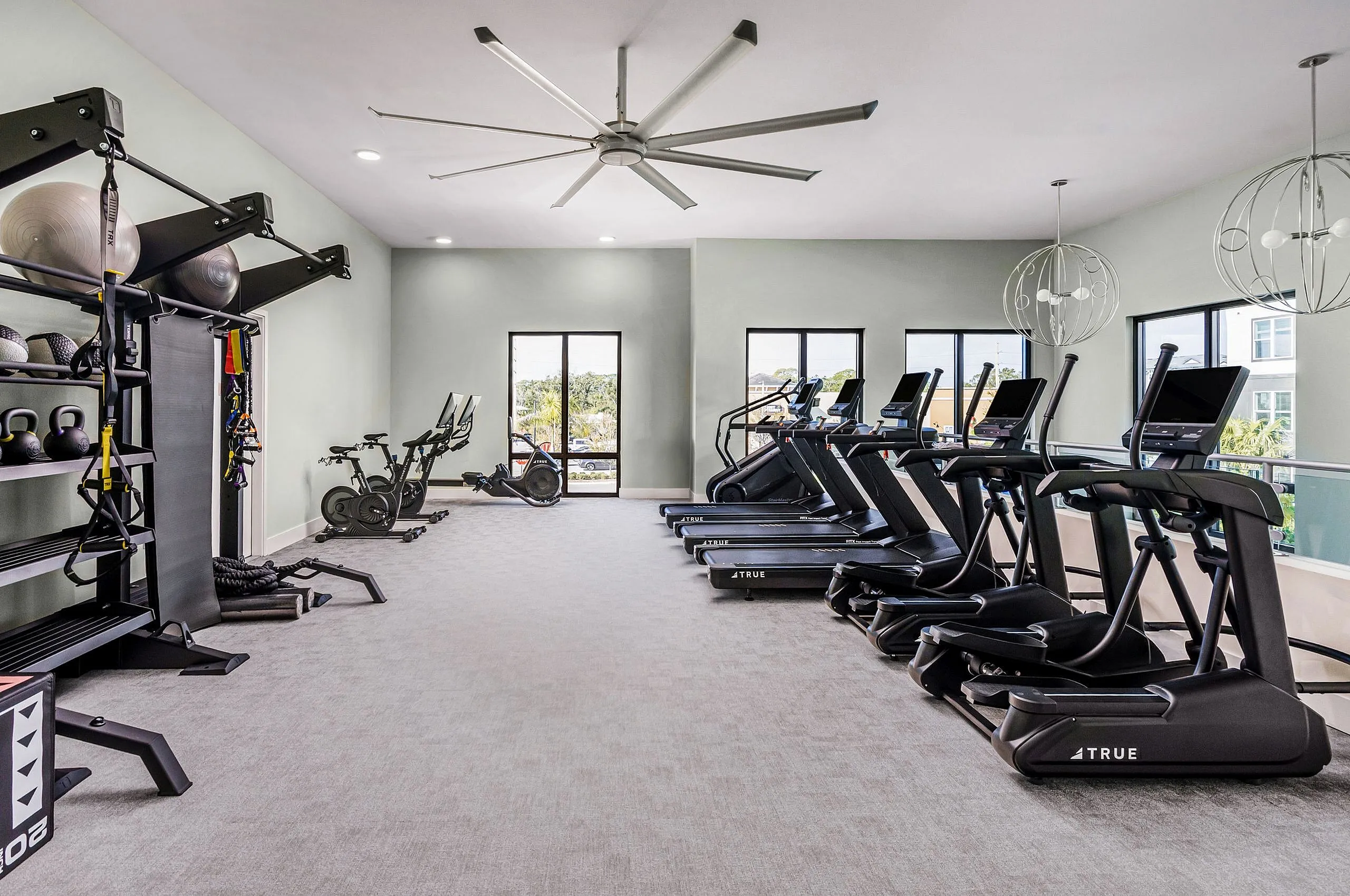 Modern fitness center with state-of-the-art treadmills, exercise bikes, and a variety of strength training equipment, enhanced by natural light and sleek design.