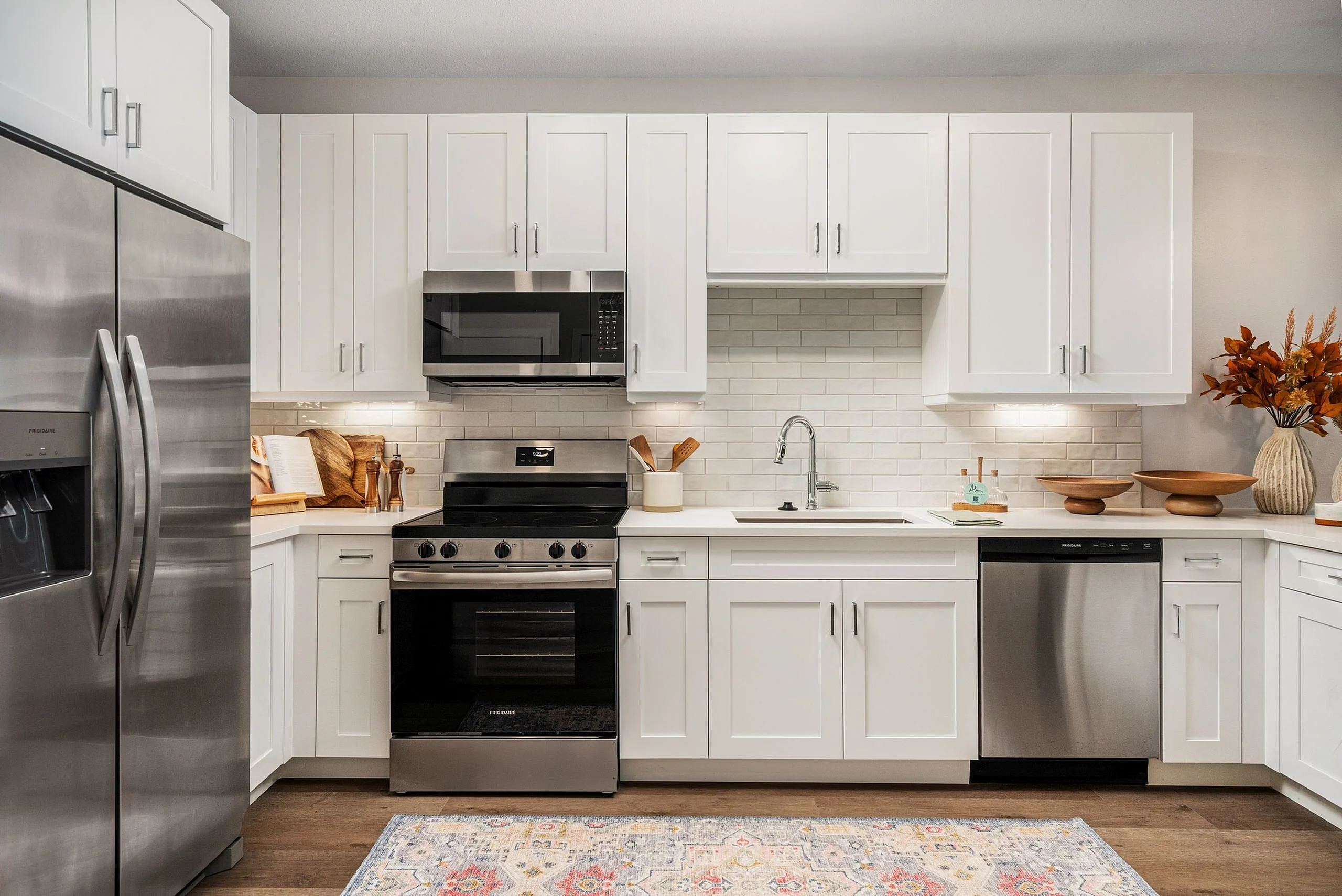 Elegant modern kitchen with white cabinets, stainless steel appliances, and stylish backsplash.
