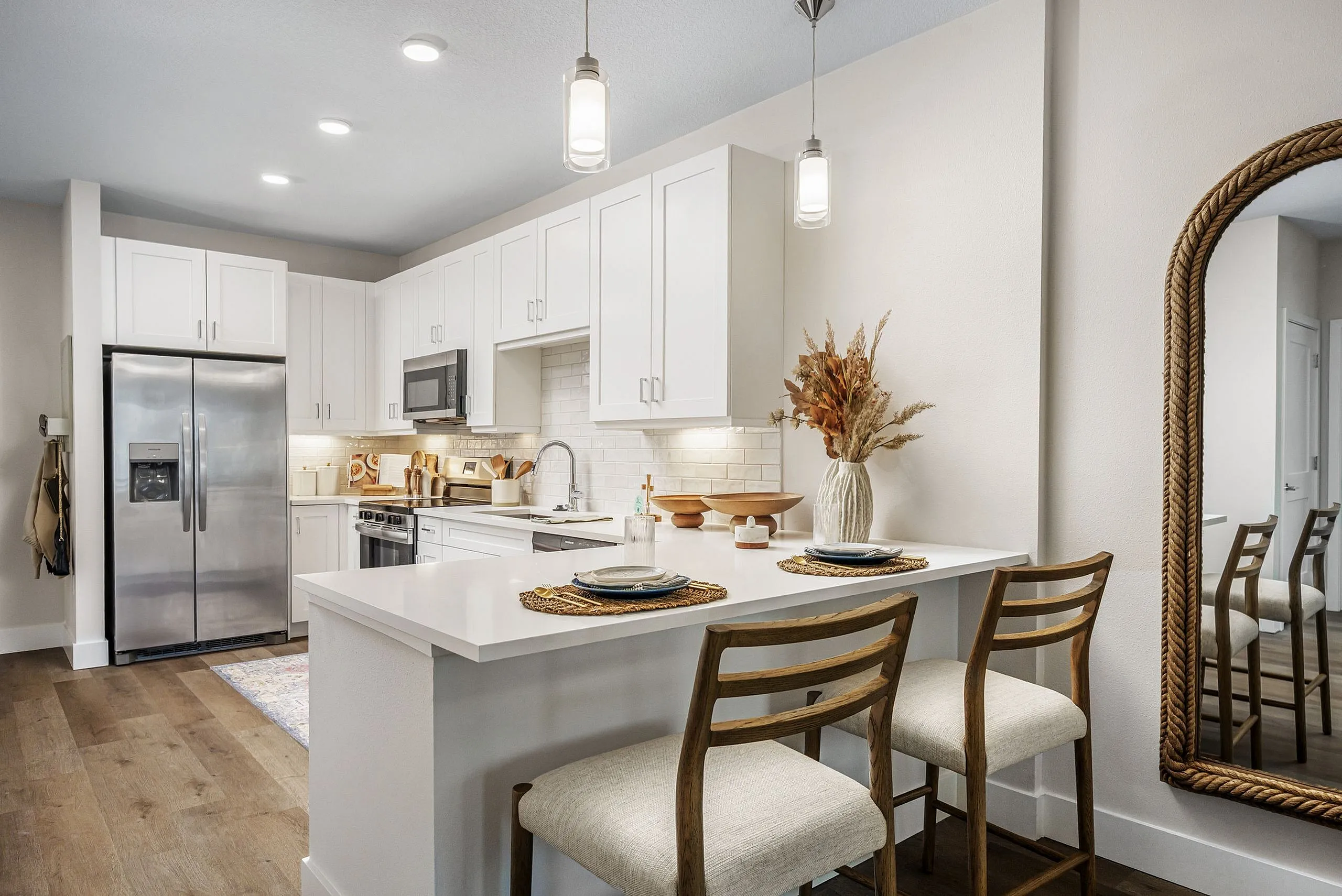 Chic modern kitchen with stainless steel appliances, sleek countertops, and elegant pendant lighting enhancing a cozy breakfast bar.