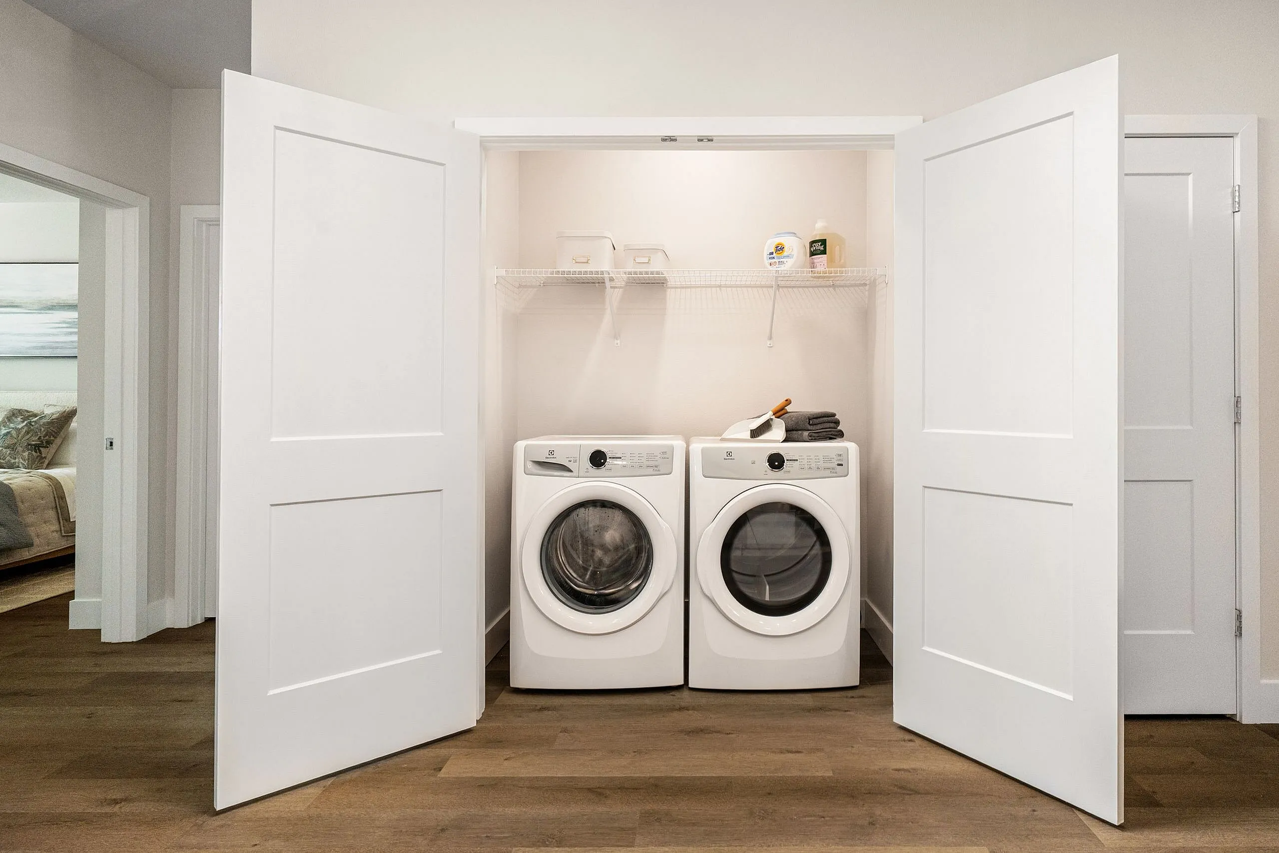 Modern laundry nook with sleek washer and dryer, featuring ample shelving in a pristine and organized space.