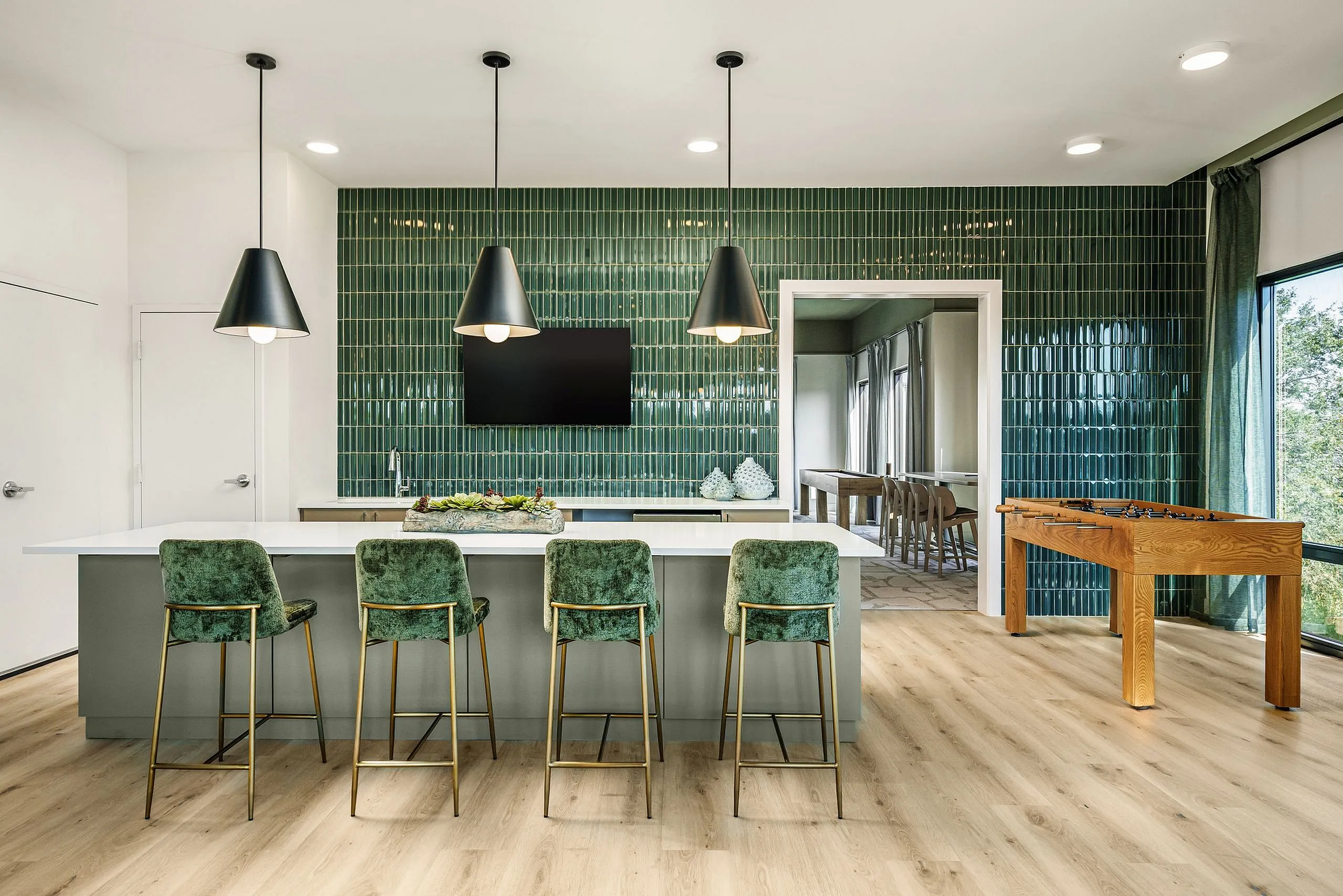 Elegant modern kitchen with a chic green tile backsplash, plush bar stools, and ambient pendant lighting, perfect for entertaining.