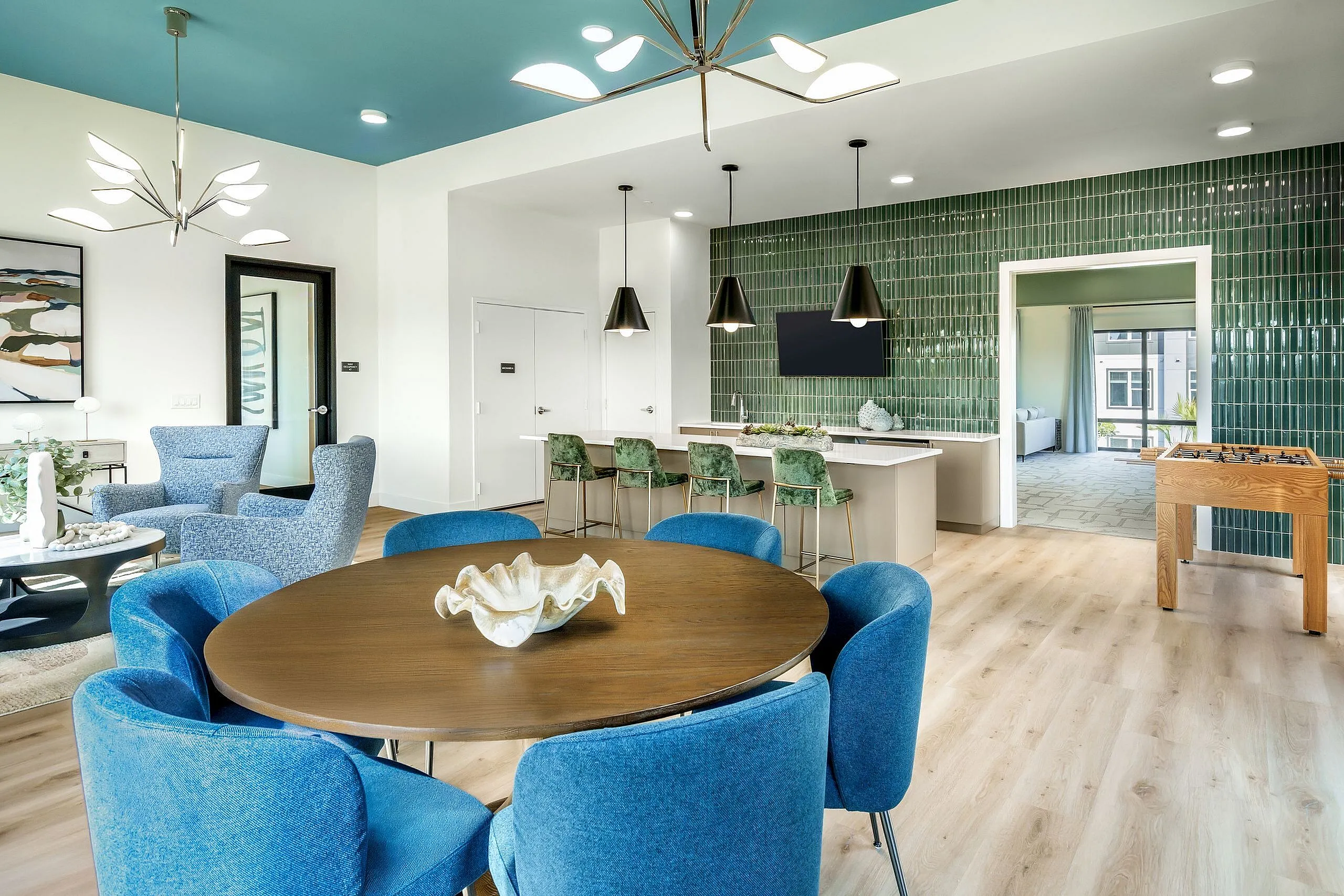 Modern apartment interior with vibrant blue and green color accents, featuring a stylish dining area, cozy seating, and open kitchen.