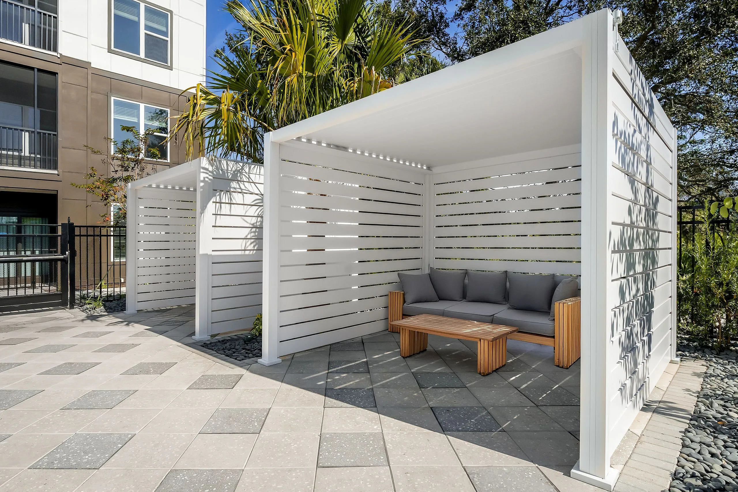 Chic outdoor lounge area with modern pergolas, comfortable seating, and lush greenery, ideal for relaxation.