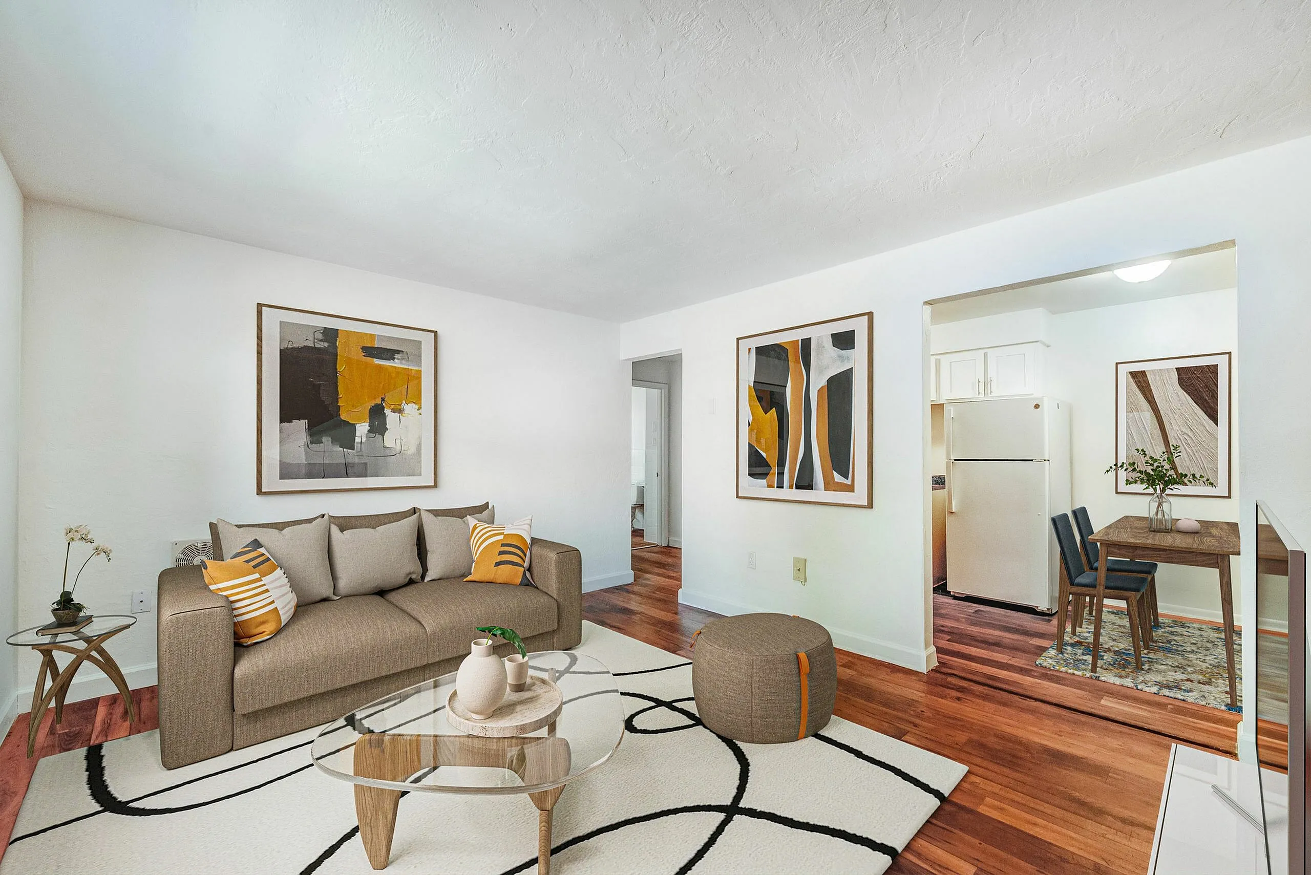 Inviting living space with modern art, cozy brown sofa, and open layout to a chic kitchen area. Perfect blend of style and comfort.