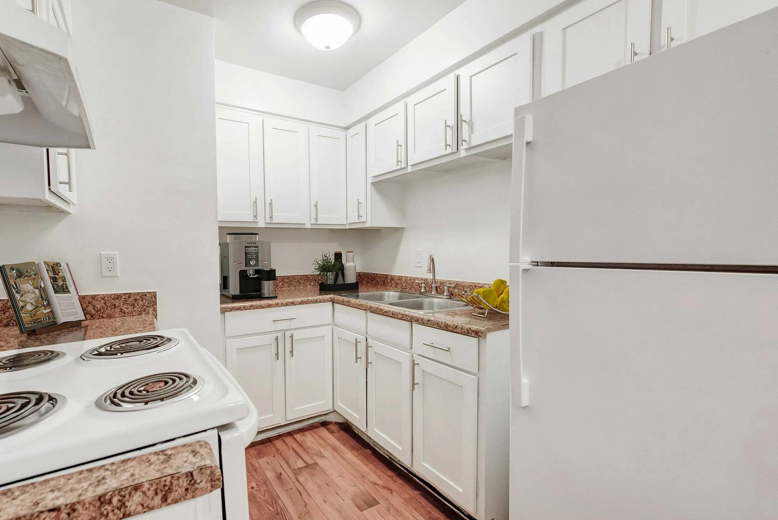 Charming kitchen with modern white cabinetry, sleek countertops, and cozy wood flooring for a welcoming atmosphere.