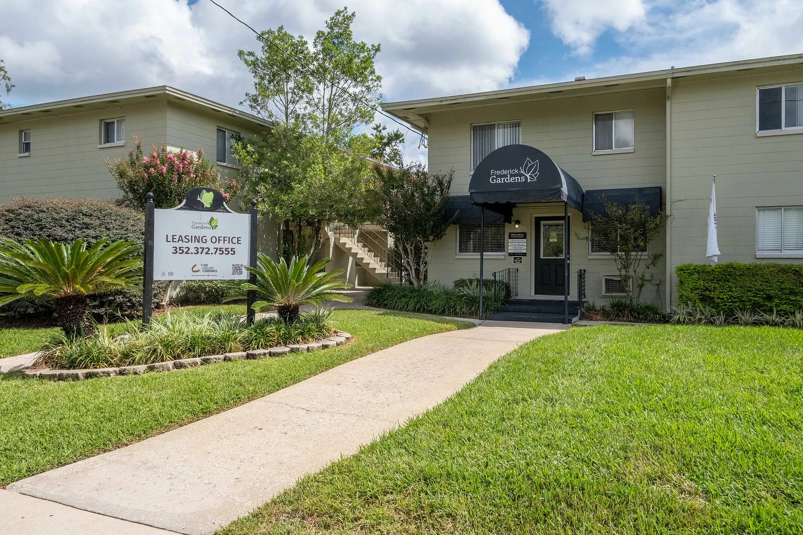 Inviting entrance to Frederick Gardens featuring lush landscaping, a welcoming path, and a stylish leasing office under a modern awning.