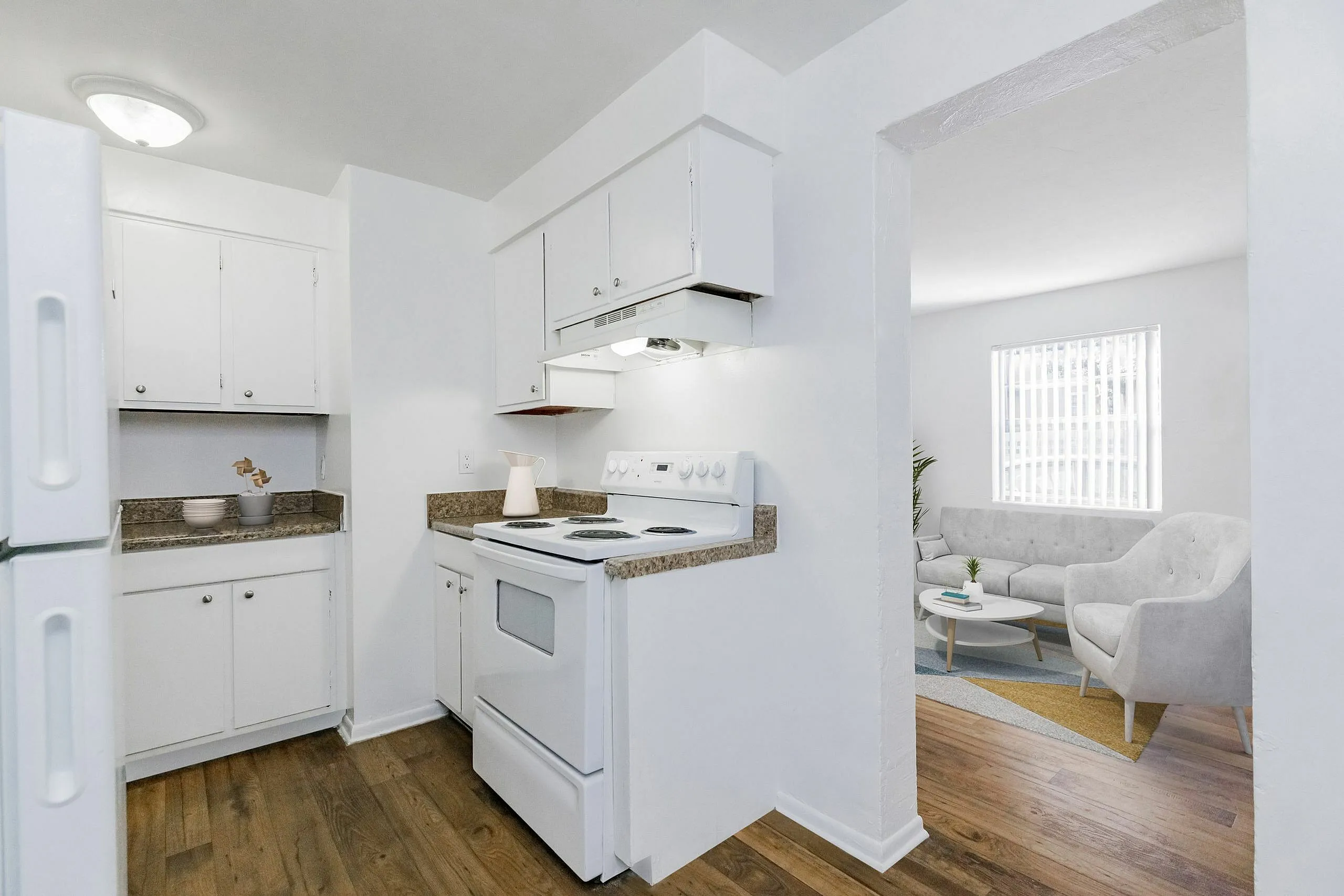 Bright open kitchen with sleek countertops, leading to a cozy living area with modern seating and natural light.