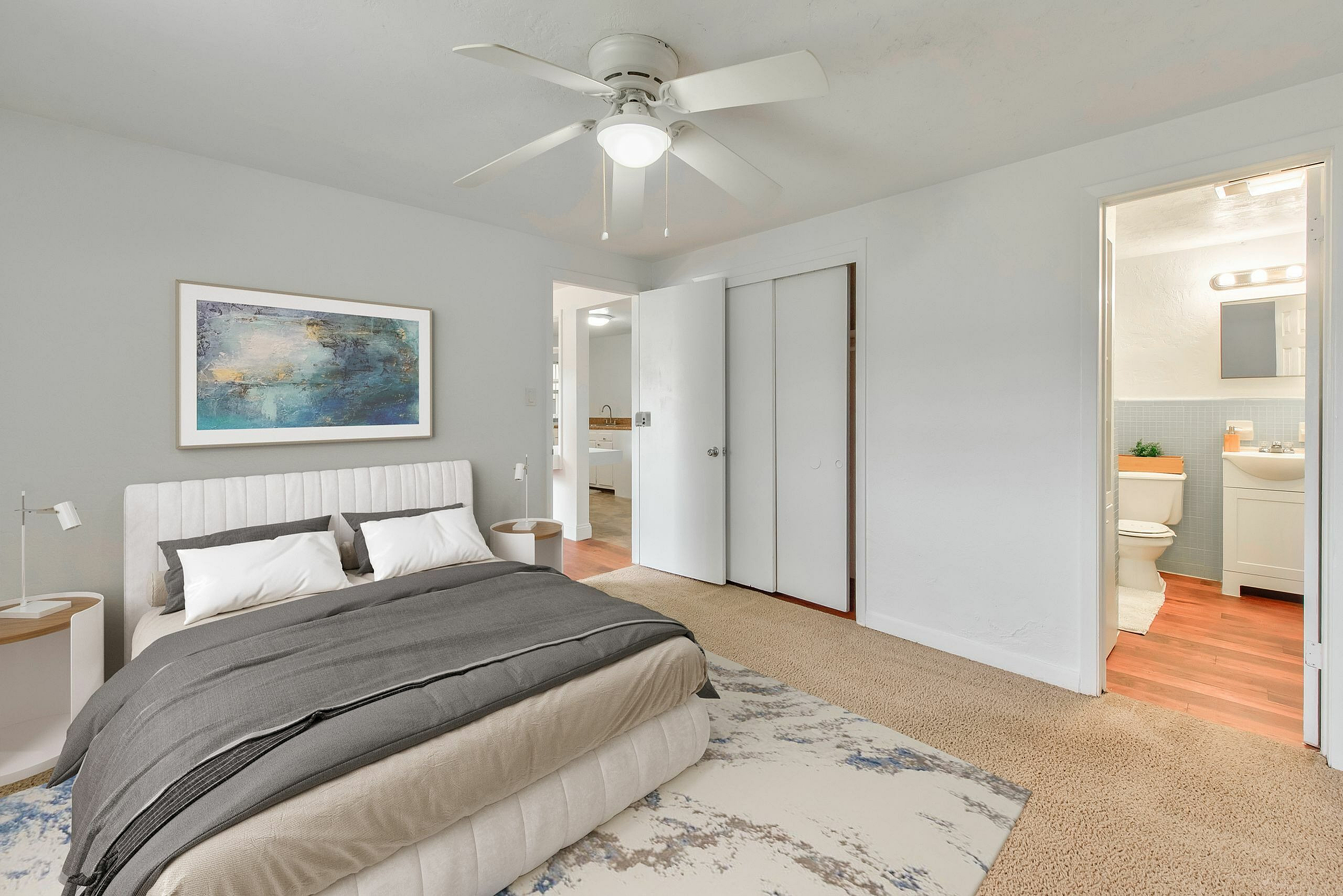 Bright and inviting bedroom with elegant decor, plush bedding, modern ceiling fan, and en-suite bathroom access.