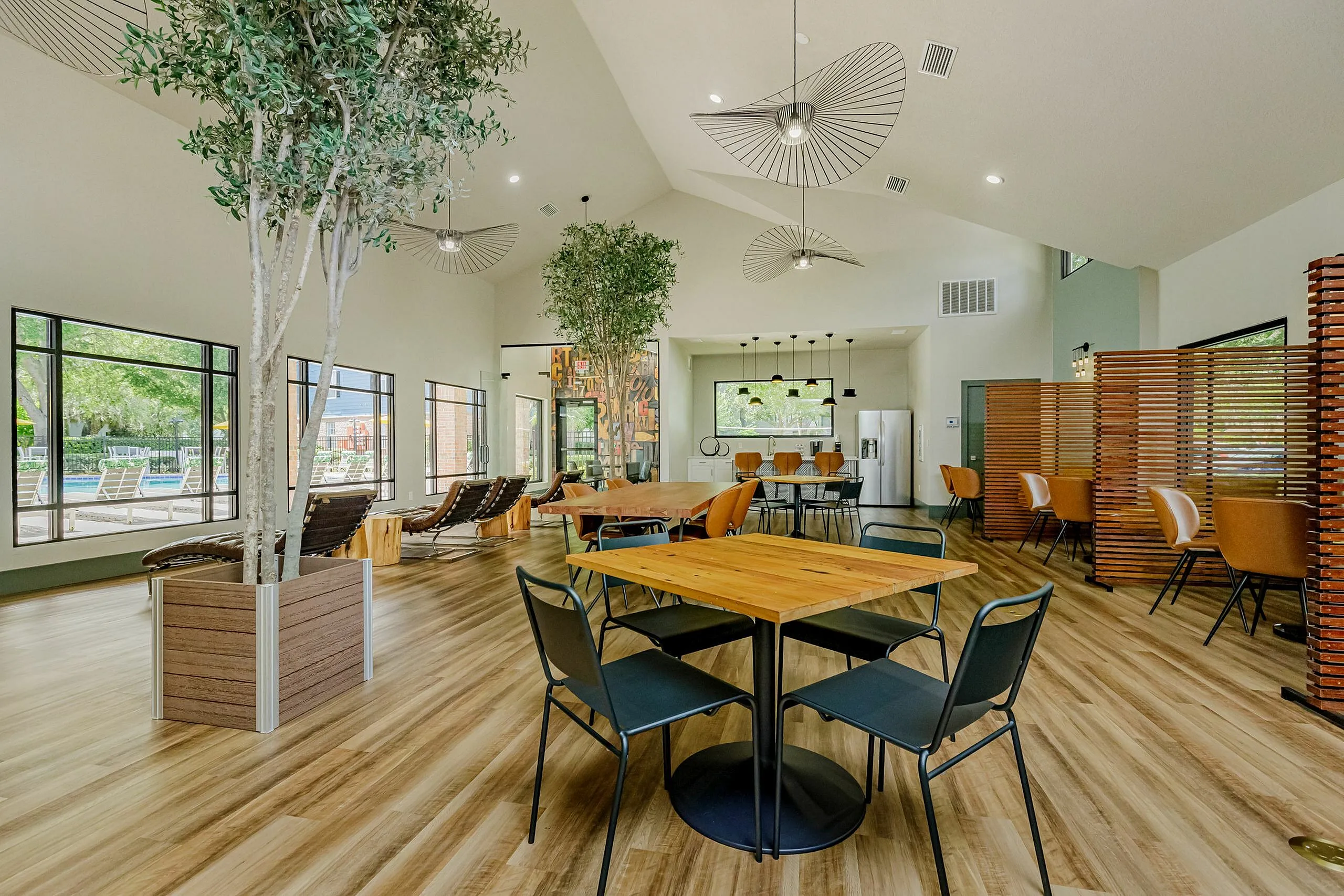 Inviting and spacious community lounge with modern decor, large windows for natural light, stylish seating, and a contemporary kitchen area.