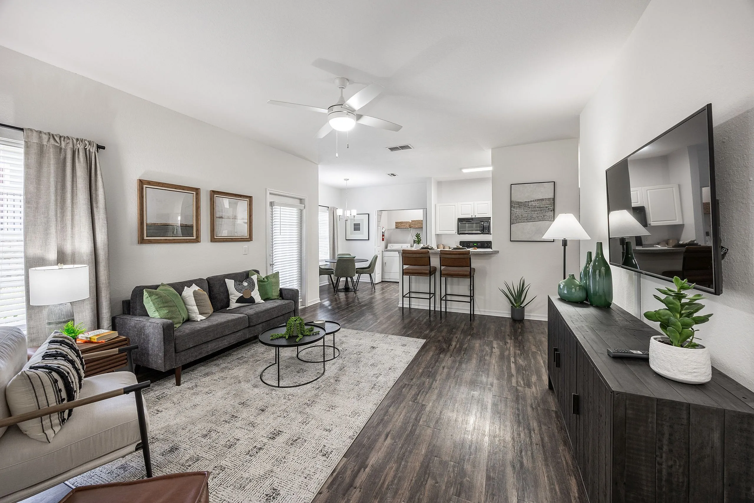 Welcoming open-concept living room with modern decor, cozy seating, and a stylish kitchen in the background.