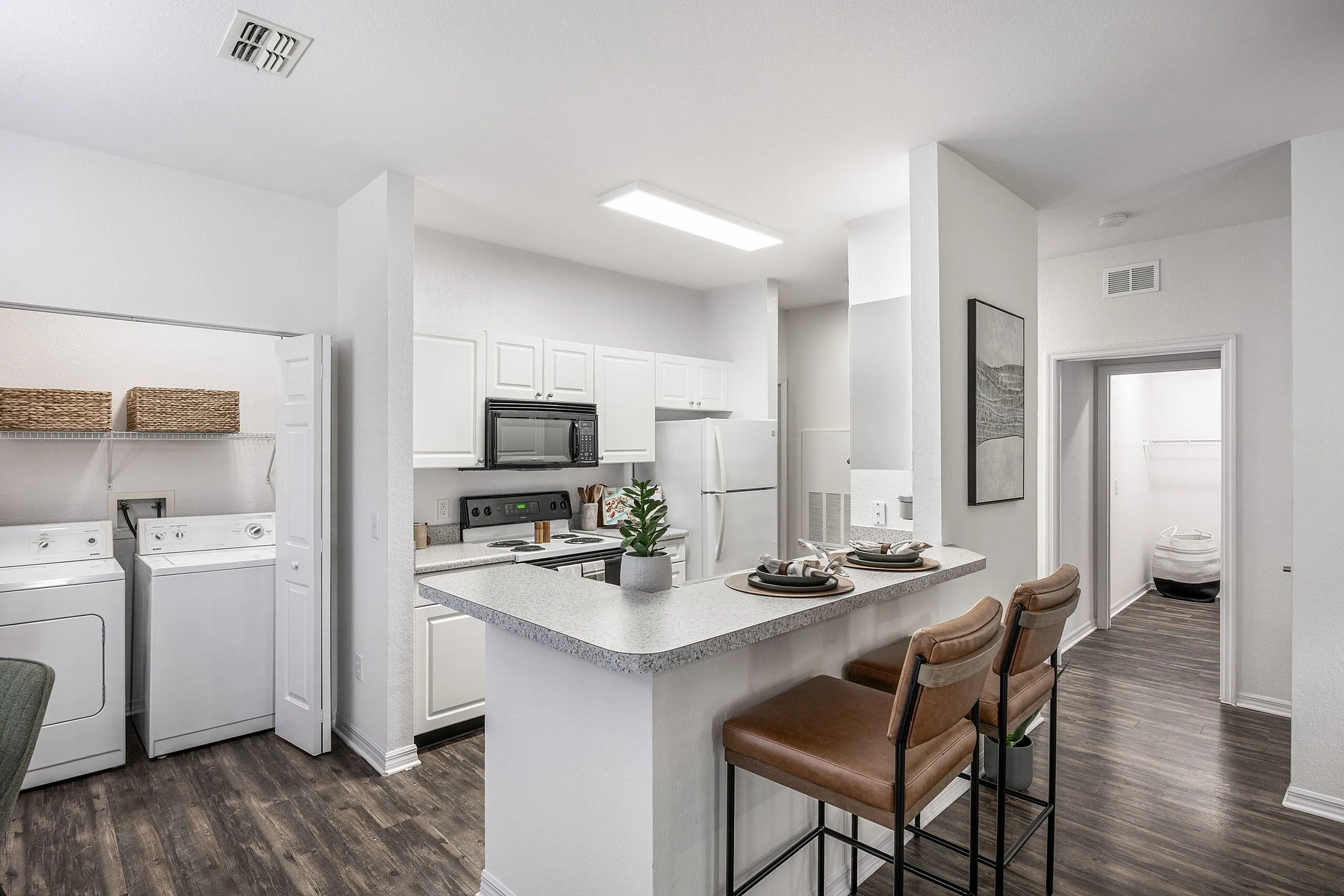 Modern apartment kitchen with sleek countertops, stylish bar seating, and in-unit laundry for convenience.