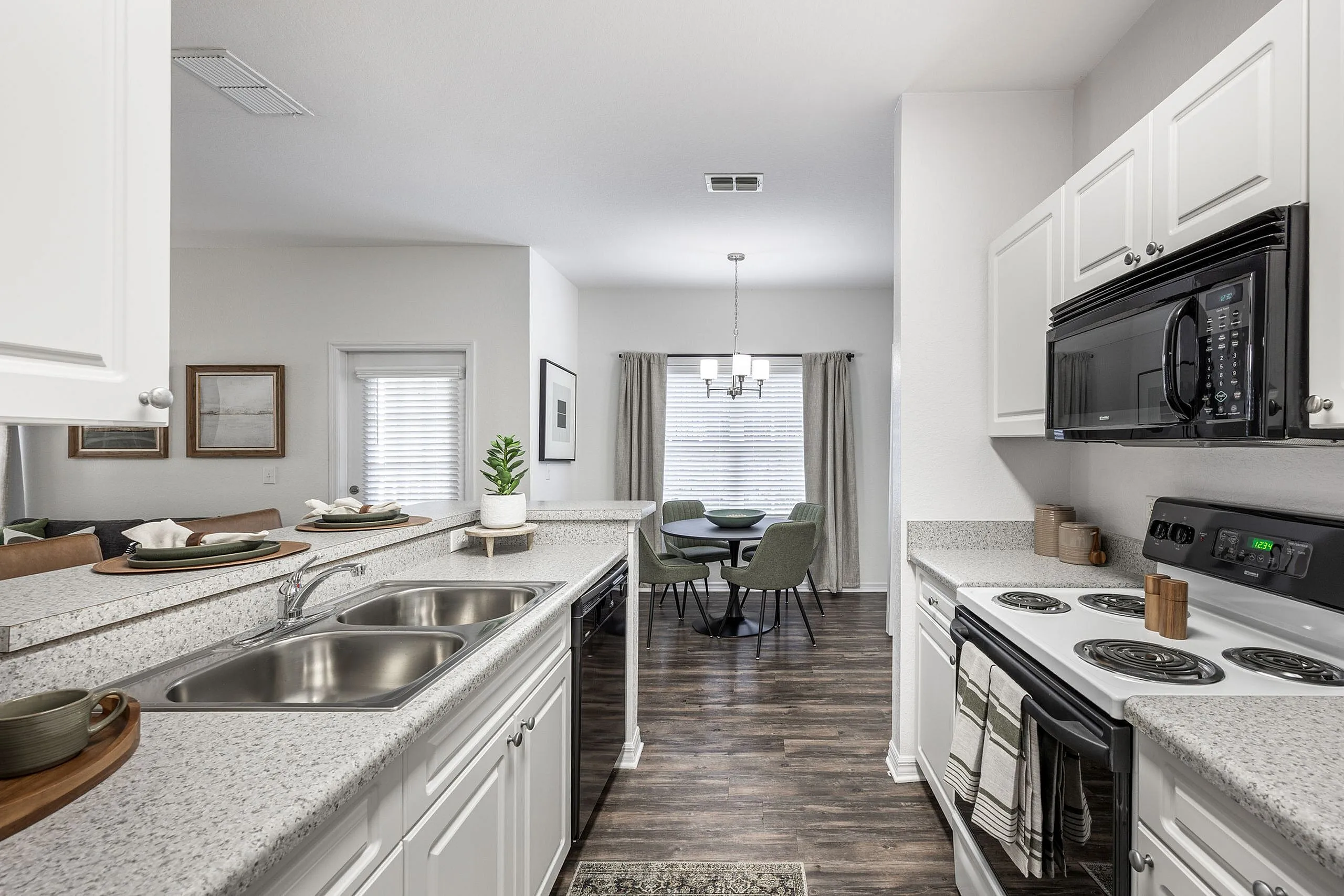 Contemporary apartment kitchen with sleek white cabinetry, spacious countertop, and adjoining dining area featuring elegant decor.