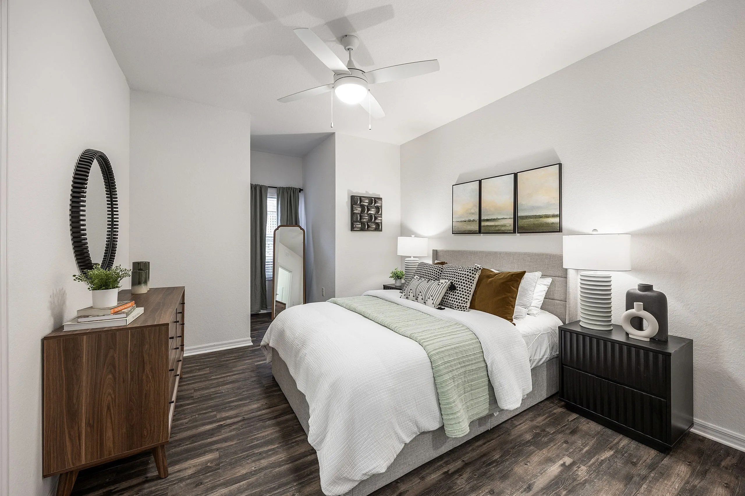 Elegant bedroom featuring a cozy bed with decorative pillows, stylish wooden dresser, and modern art decor, perfect for relaxation and comfort.
