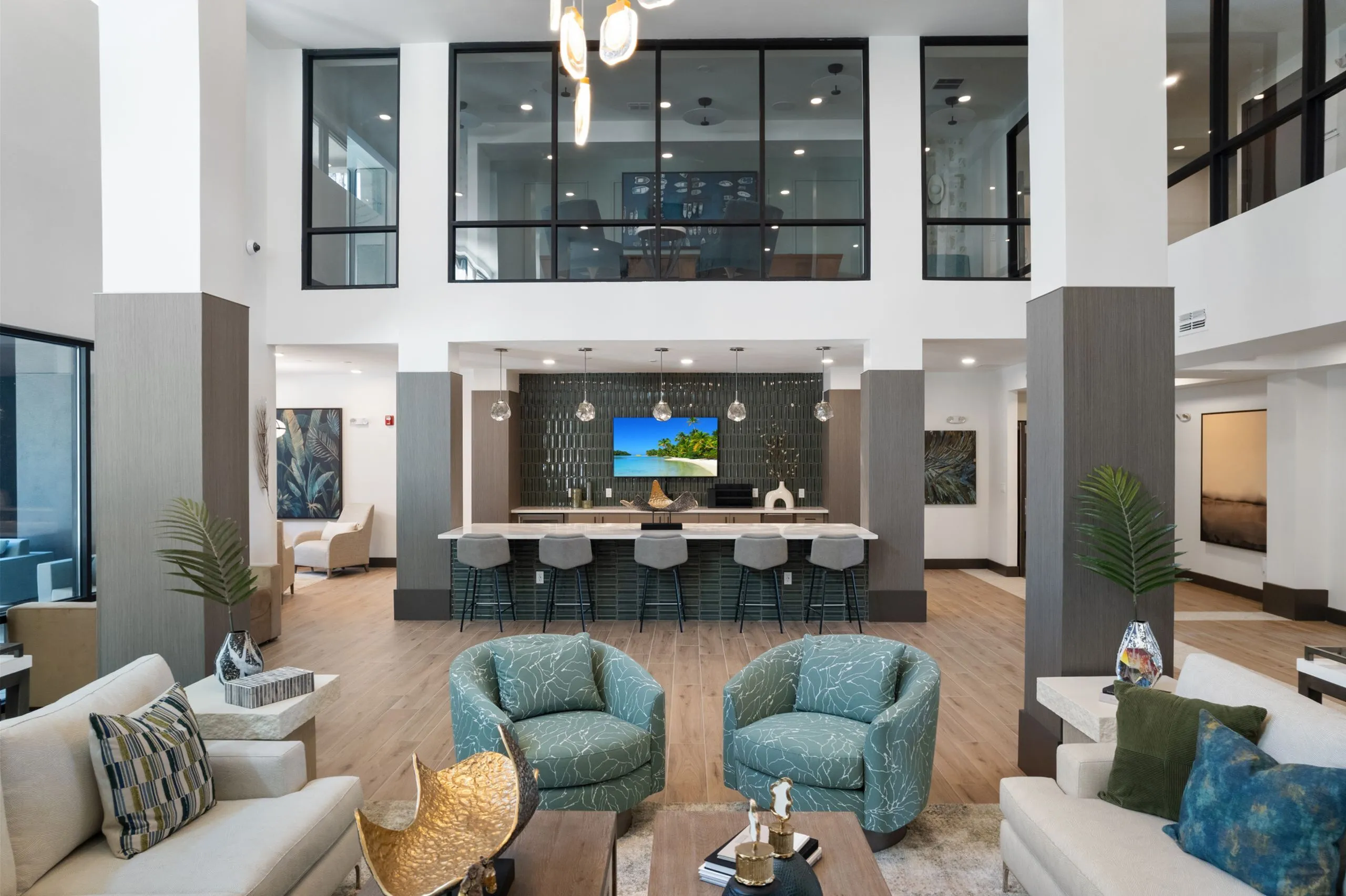 Elegant modern lounge area with chic seating, stylish decor, and a sleek kitchen bar under high ceilings.