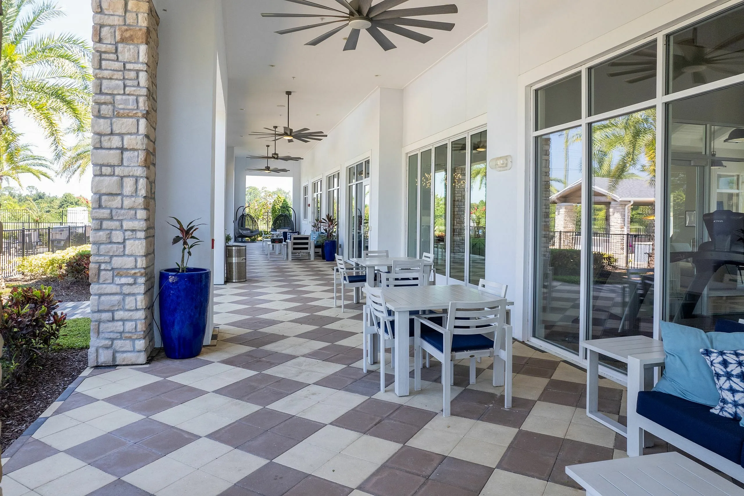 Elegant outdoor patio with stylish seating, blue accents, and overhead fans, perfect for relaxation and social gatherings.
