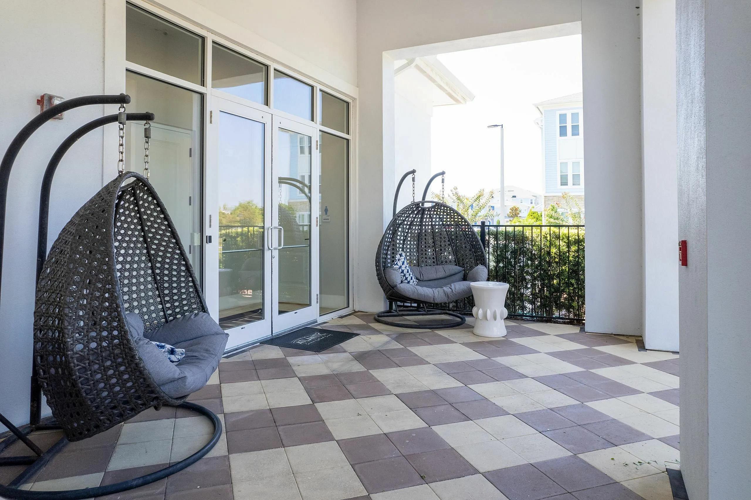 Inviting patio space with stylish hanging chairs, chic tiled flooring, and a serene view, perfect for relaxing.