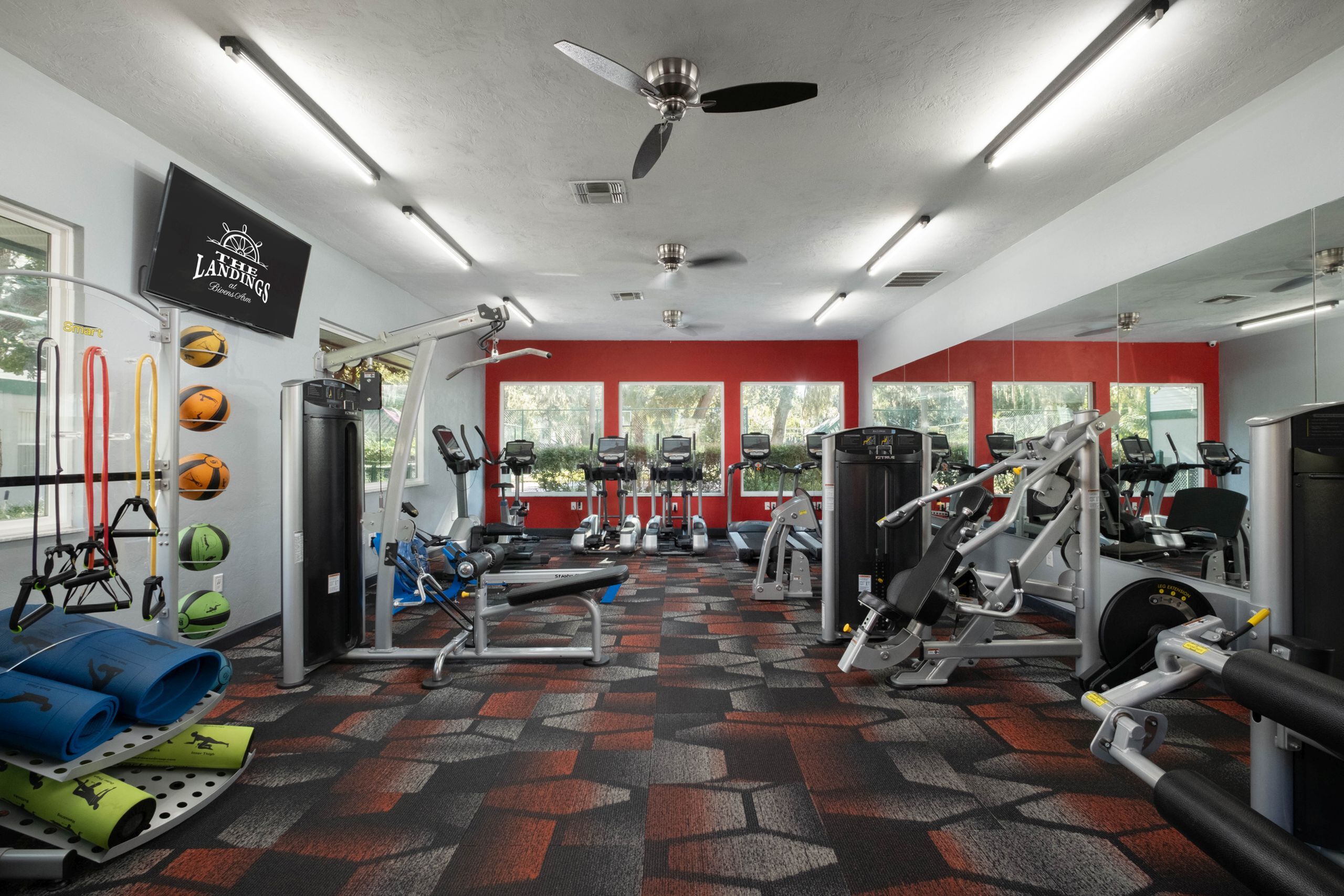 Bright, modern fitness center featuring top-of-the-line equipment, vibrant flooring, and large windows for natural light.
