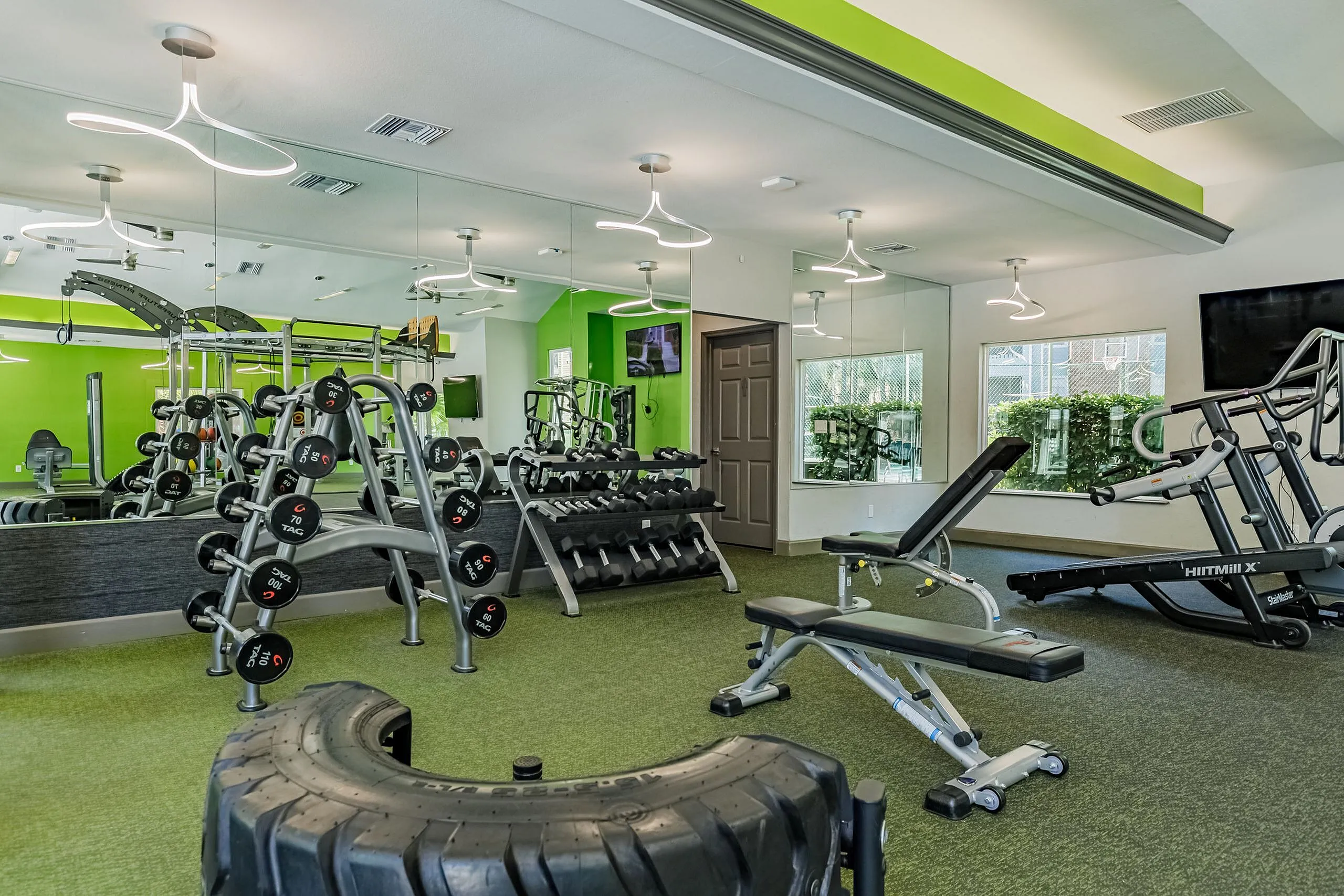 Modern fitness center with vibrant green accents, featuring weight racks, exercise machines, and sleek lighting for an energizing workout experience.
