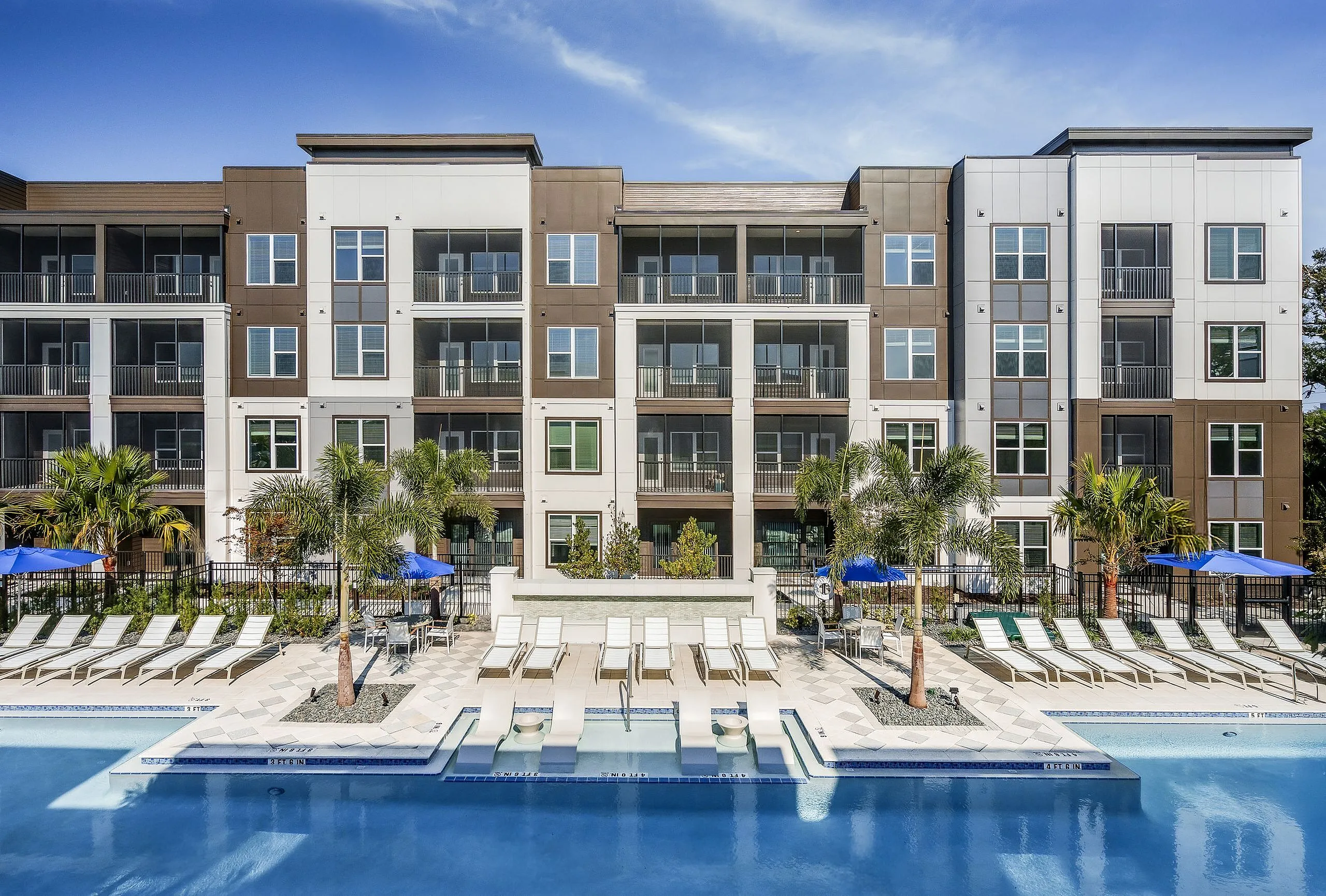 Contemporary apartment complex with poolside luxury featuring sleek architecture, lush palm trees, and sunny lounge area perfect for relaxation.