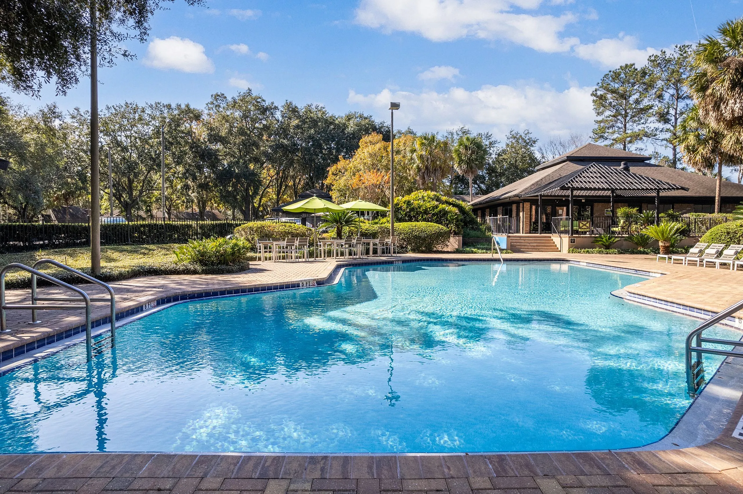 Inviting pool area surrounded by lush greenery and stylish lounge chairs, perfect for relaxation and outdoor gatherings.