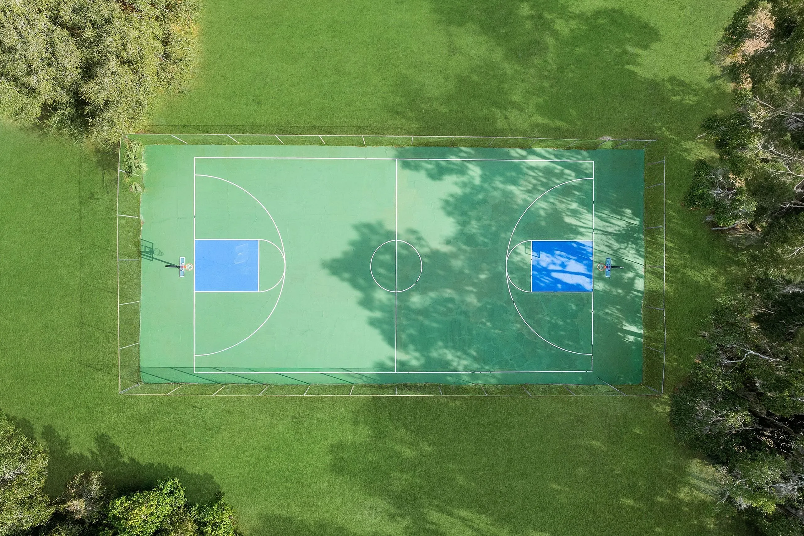 Aerial view of a vibrant outdoor basketball court surrounded by lush greenery, offering a perfect recreational escape.