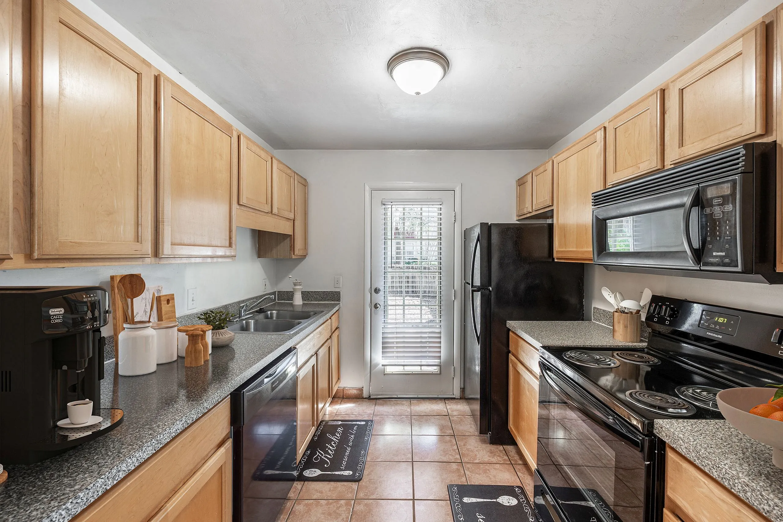 Bright and inviting kitchen with sleek black appliances, modern cabinetry, and a view to the patio through elegant French doors.