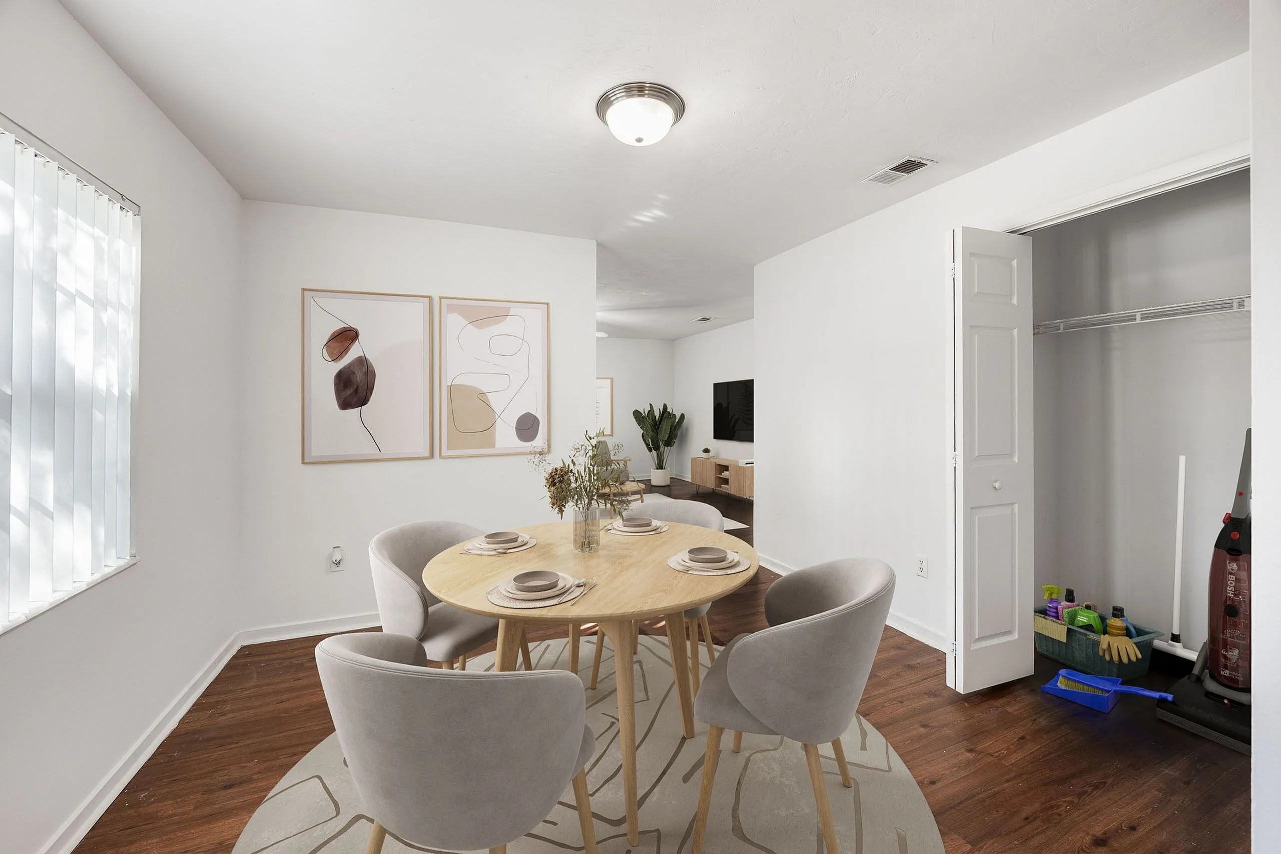 Inviting dining area with a modern round table and elegant chairs, complemented by abstract wall art and warm wooden floors, leading to a stylish living room.
