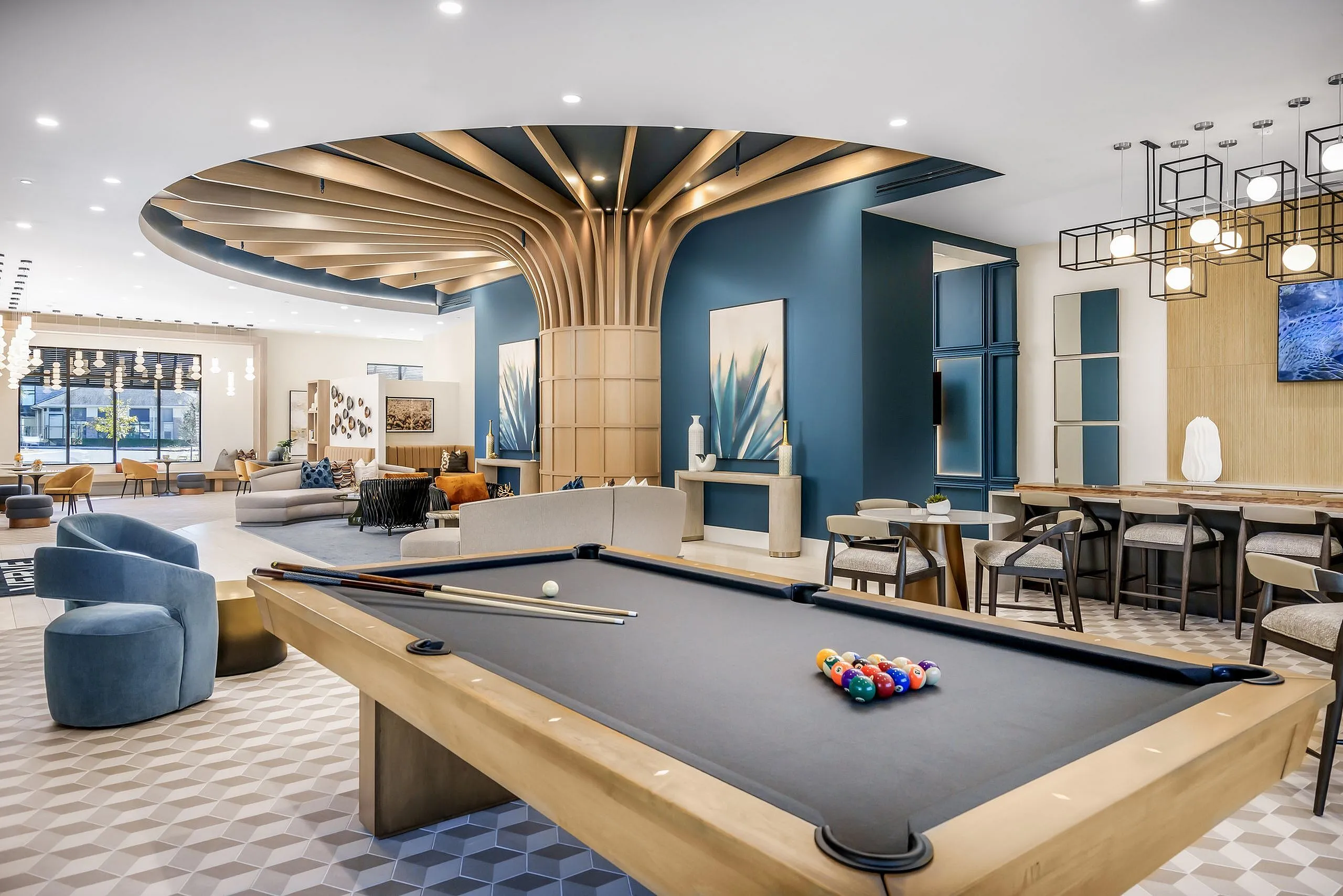 Elegant apartment lounge with stylish billiards table, modern seating, and artistic decor under a striking ceiling design.