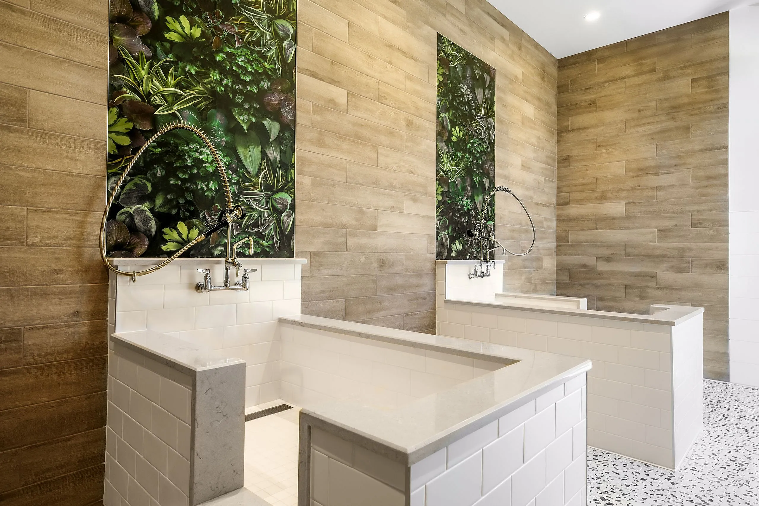 Contemporary pet washing station with sleek white tiling, elegant wood panel accents, and lush greenery, creating a stylish and functional space.