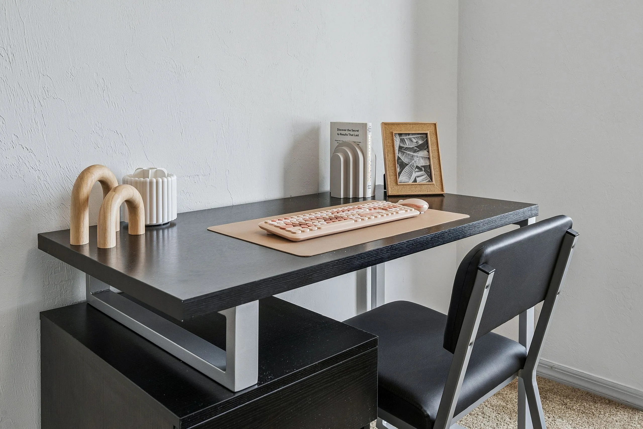 Modern home office setup with sleek black desk, comfortable chair, and chic decor items creating an inviting workspace.