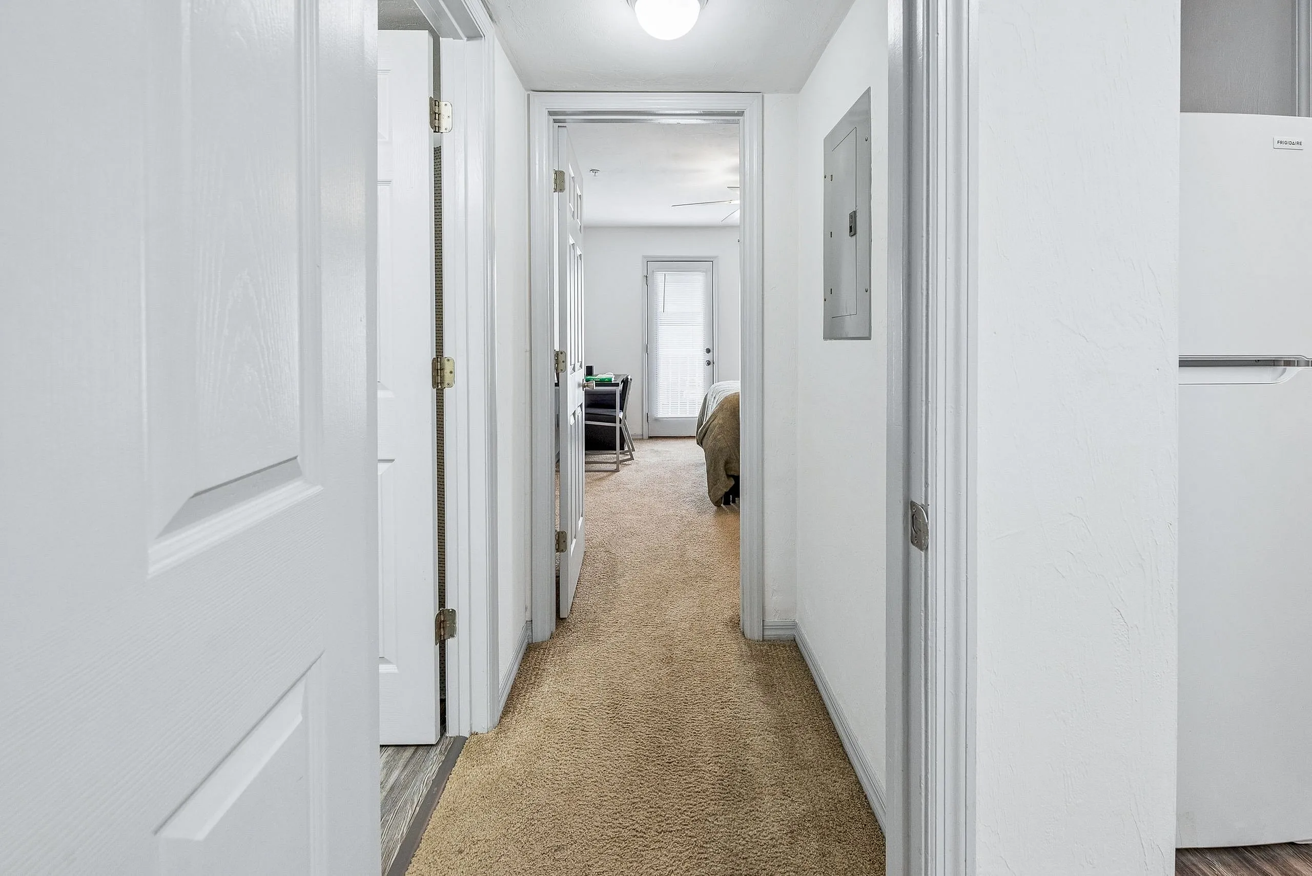 Welcoming hallway with plush carpeting leading to a cozy bedroom and stylish living area.