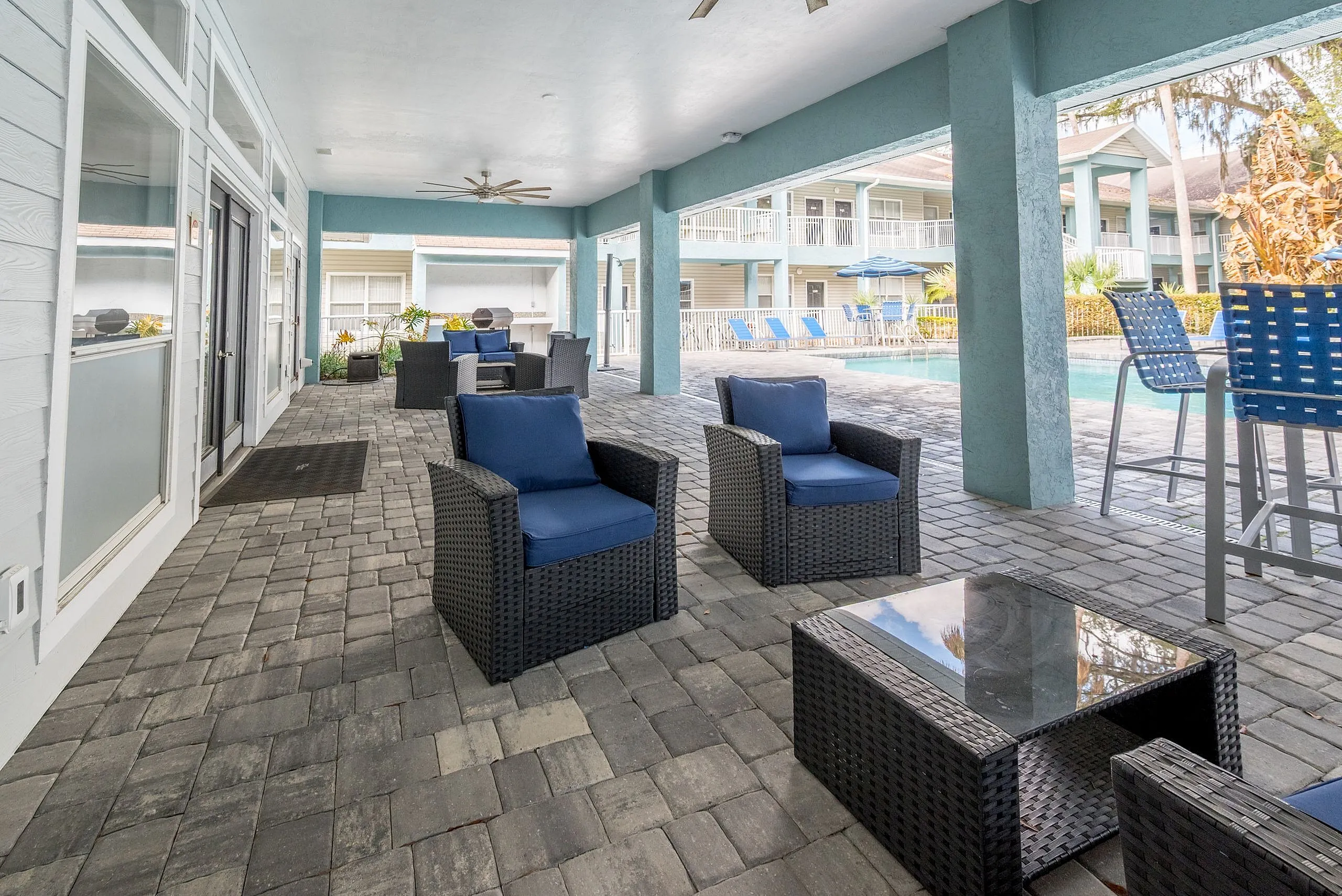 Inviting outdoor lounge area with cozy wicker furniture and poolside views, ideal for relaxation and entertainment.