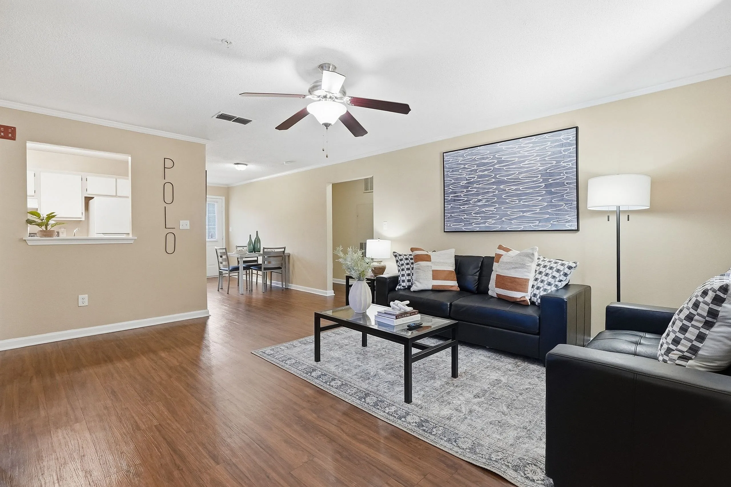 Inviting apartment with modern living room featuring sleek black couches, stylish decor, and a bright dining area with natural light.