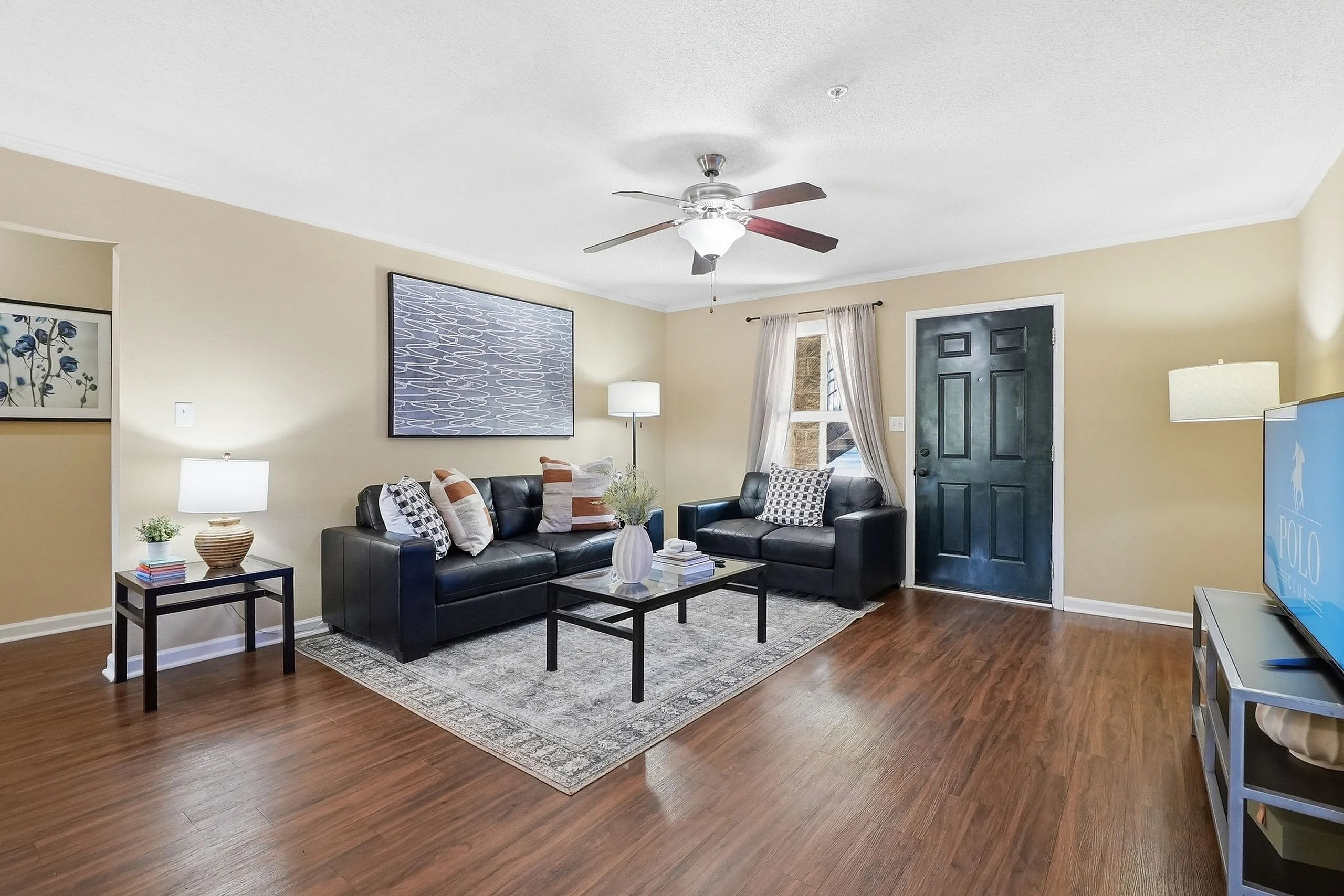Inviting living room with elegant decor, featuring plush black sofas, tasteful artwork, and a warm ambiance.
