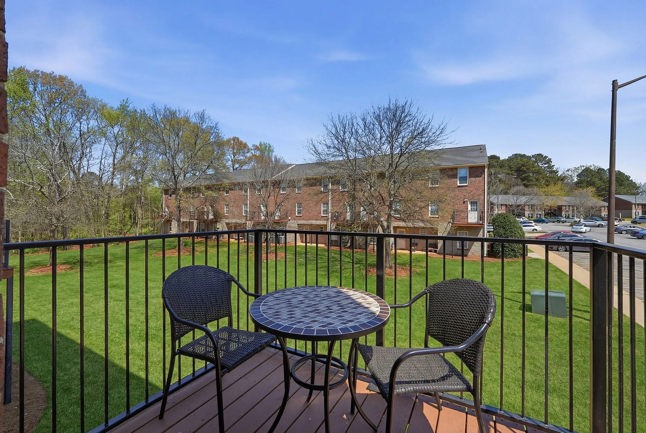 Charming balcony view with stylish seating, overlooking lush green lawns and inviting neighborhood vibes.