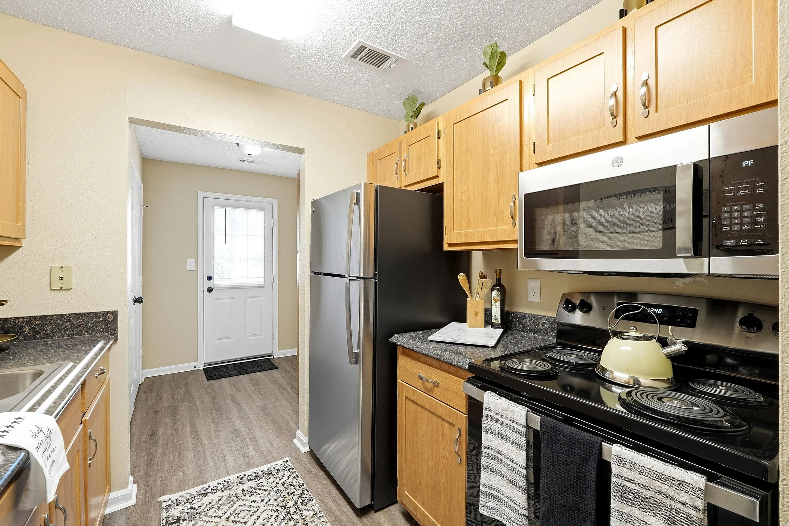Charming kitchen with stainless steel appliances, warm wood cabinetry, and modern decor, offering a cozy and functional space.