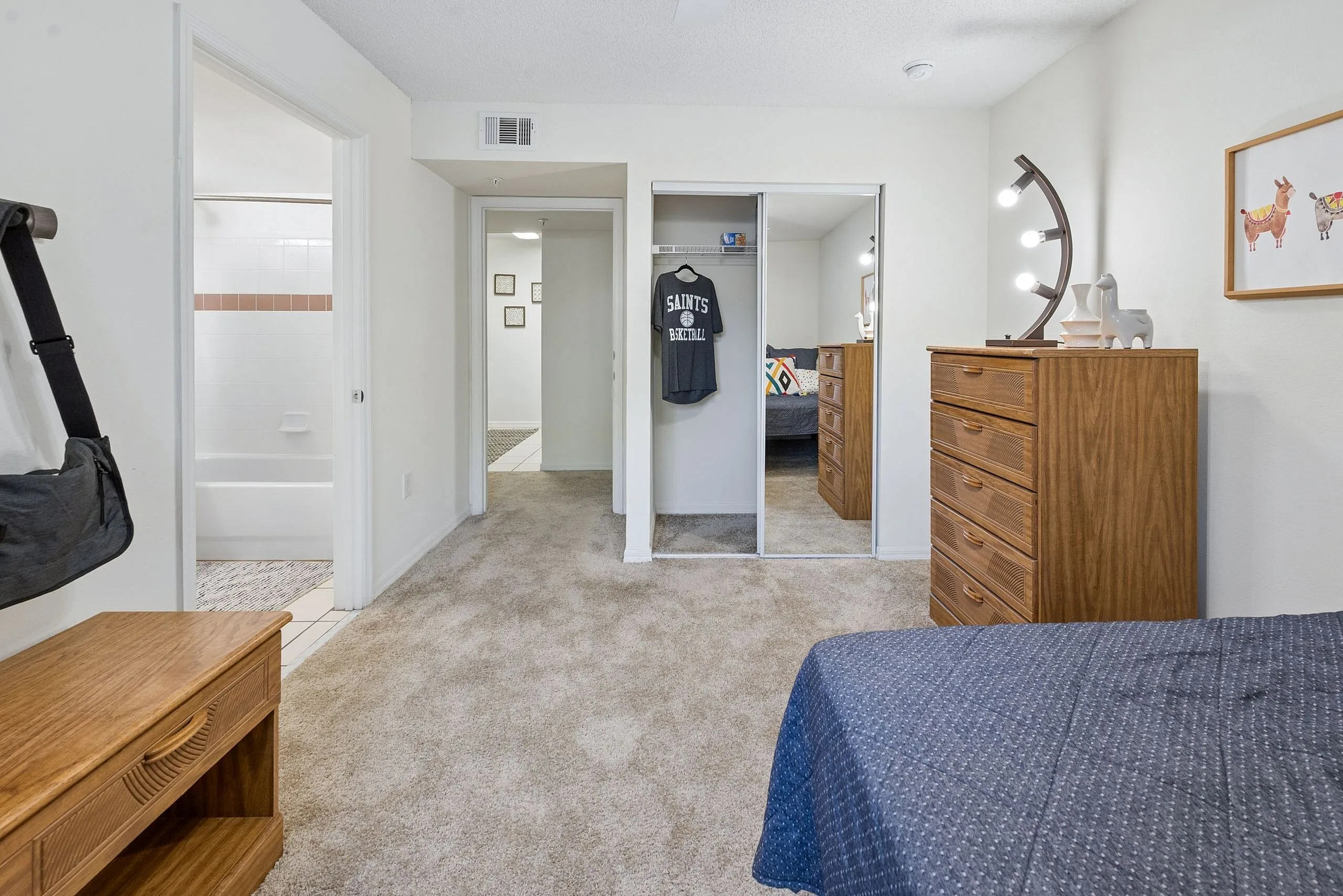 Inviting bedroom with plush carpeting, elegant wooden dressers, and ample closet space. Seamless access to bathroom and additional room enhances convenience.