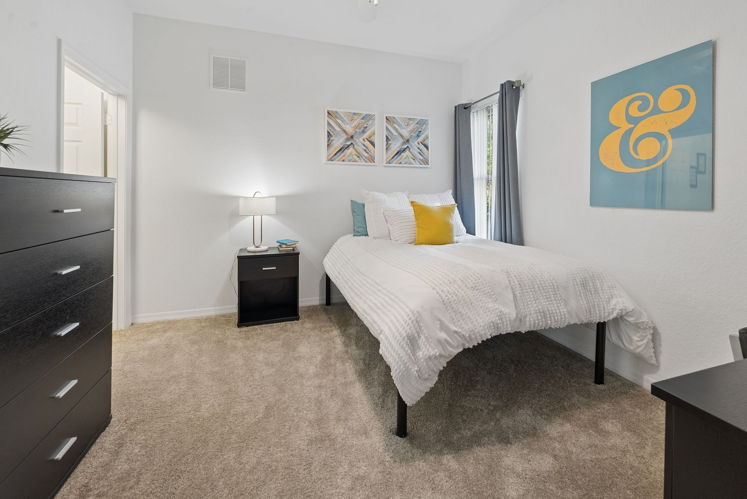 Bright and cozy bedroom with elegant decor, featuring a comfortable bed, modern furniture, and vibrant wall art.