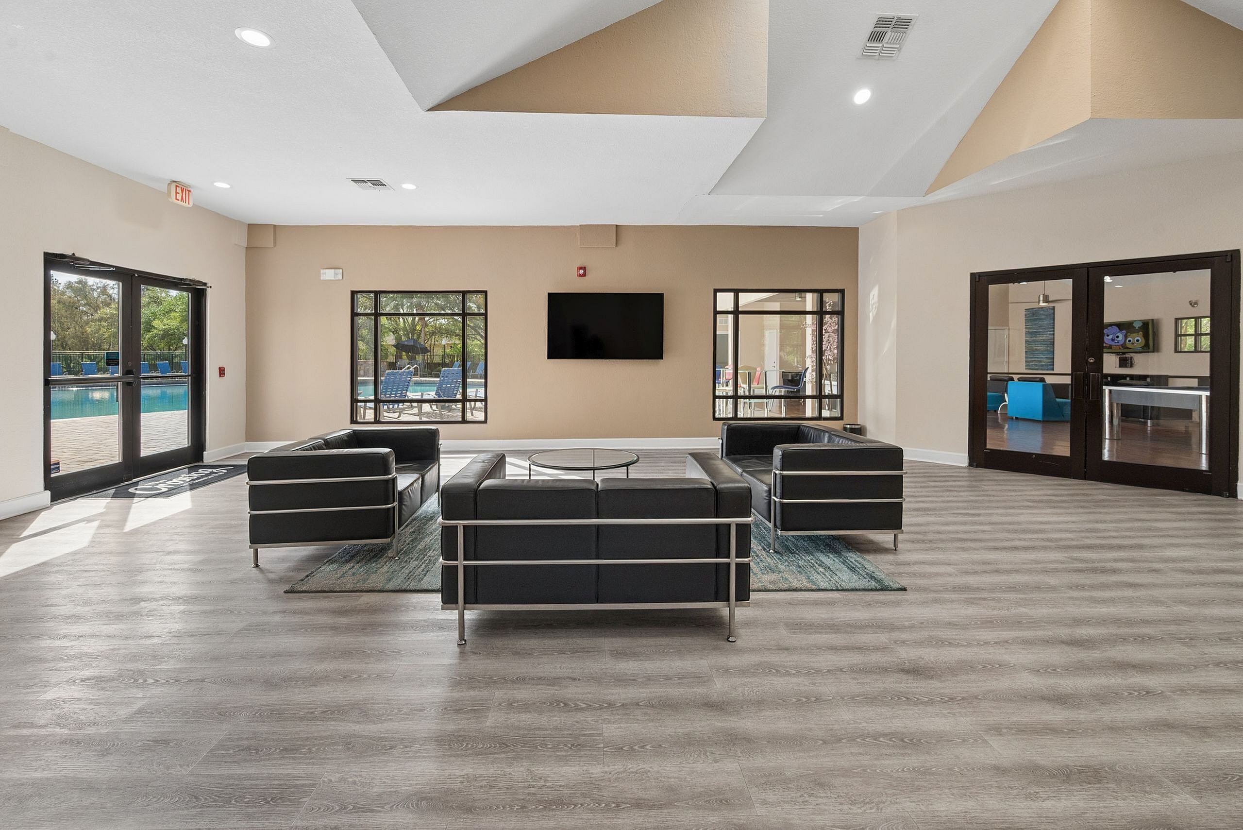 Inviting community room with modern black seating, large windows, and a view of the swimming pool outside.