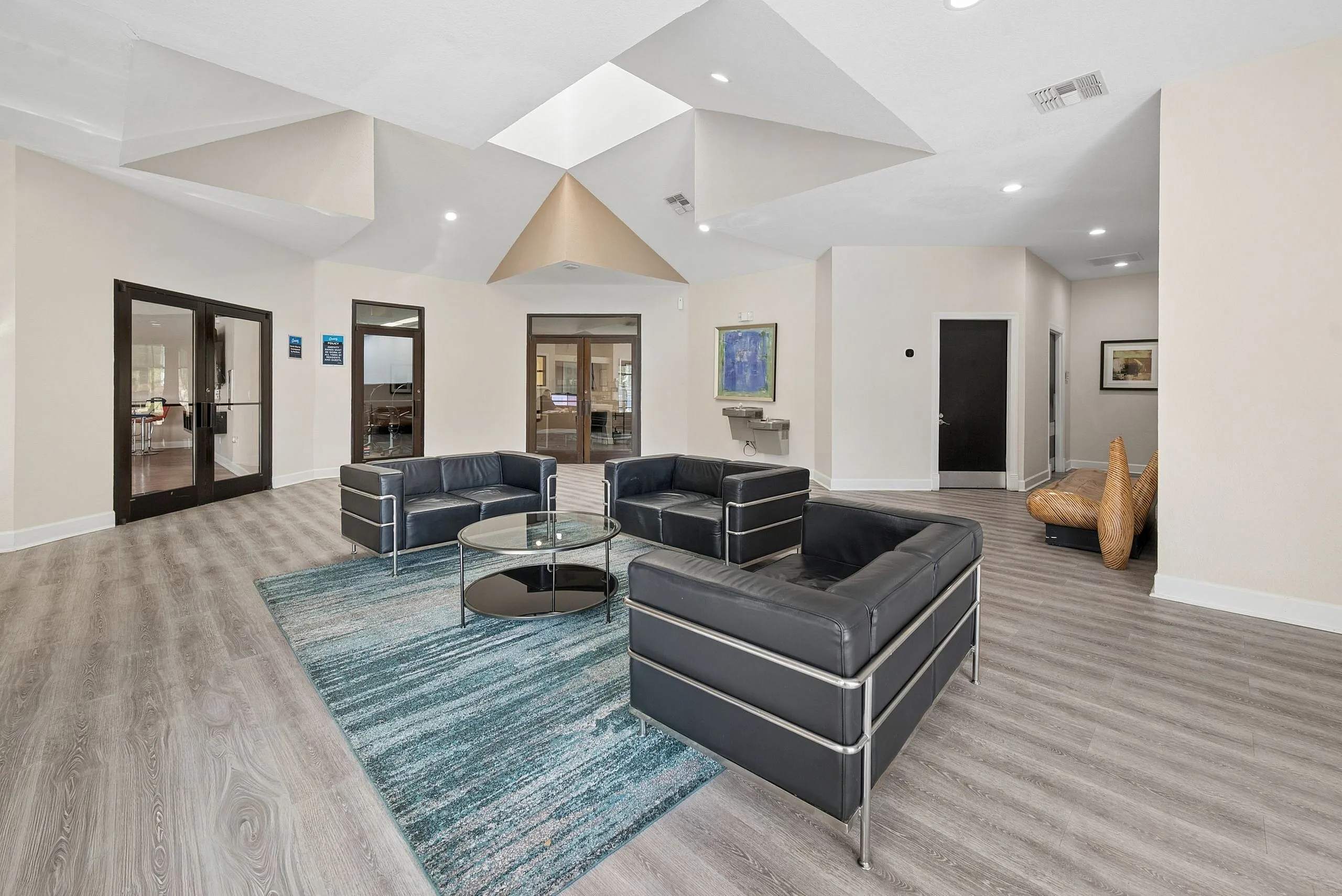 Elegant lounge area with modern black sofas and glass coffee table surrounded by a serene atmosphere and stylish decor.