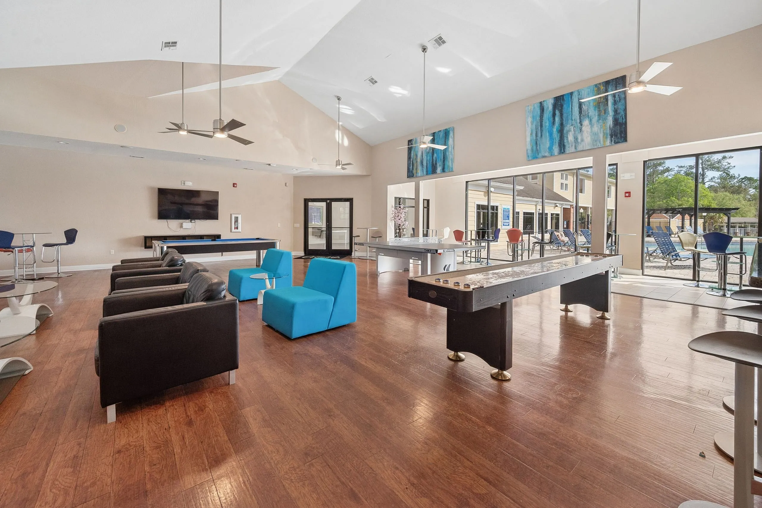 Modern communal space featuring sleek seating, expansive windows, and recreational amenities with poolside view.