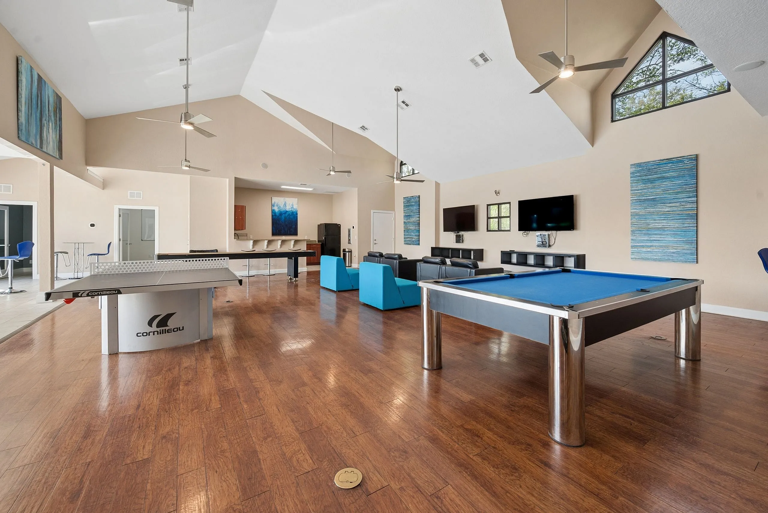 Inviting recreational room with sleek ping pong and pool tables, comfortable seating, and modern decor enhancing entertainment ambiance.